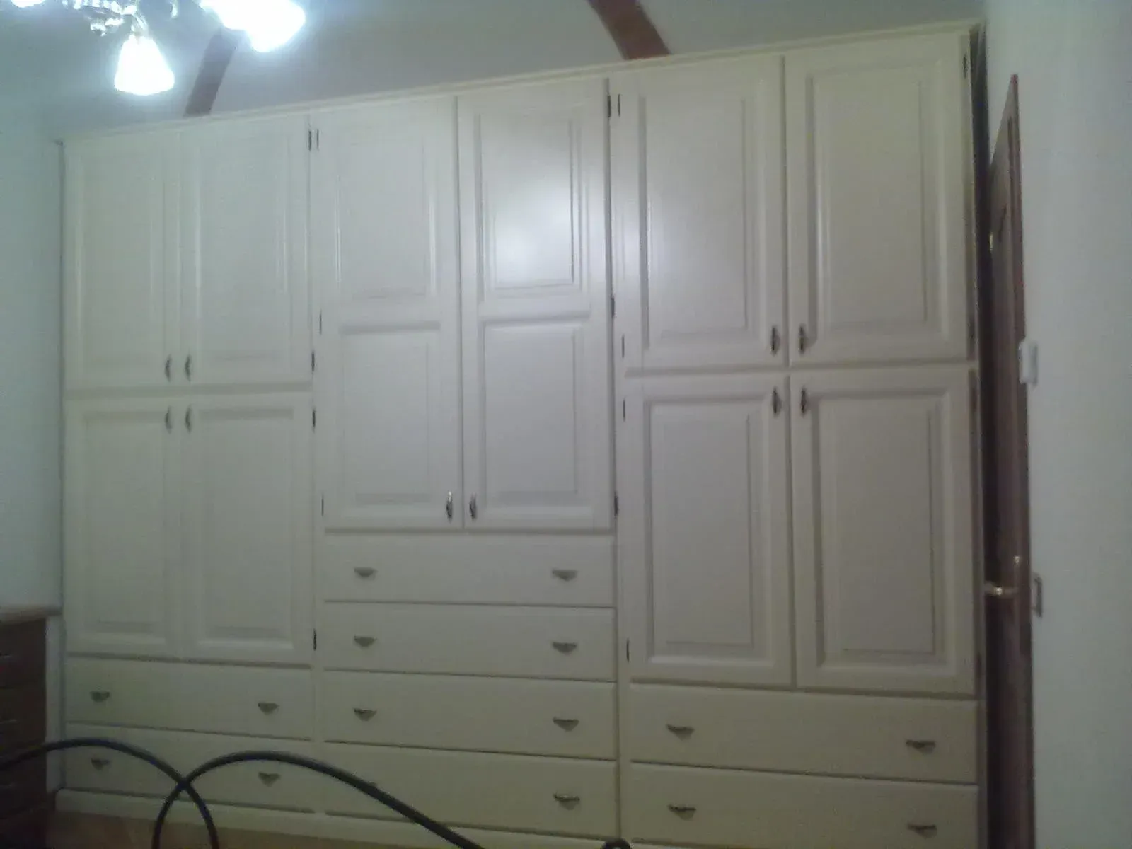 Armadio a muro color crema con più ante e cassetti in una camera da letto.