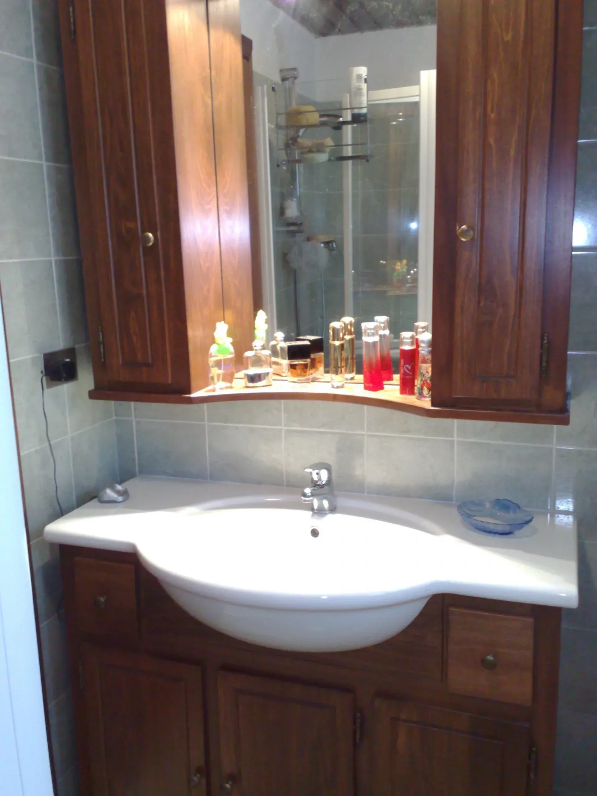 Mobiletto del bagno con mobiletto in legno, lavandino ovale e armadietto dei medicinali con specchio.