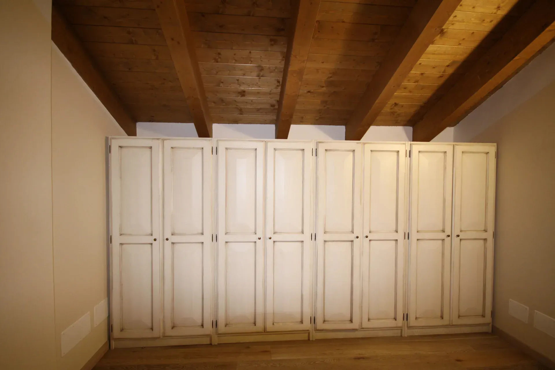 Ante bianche dell'armadio sotto un soffitto con travi in ​​legno.