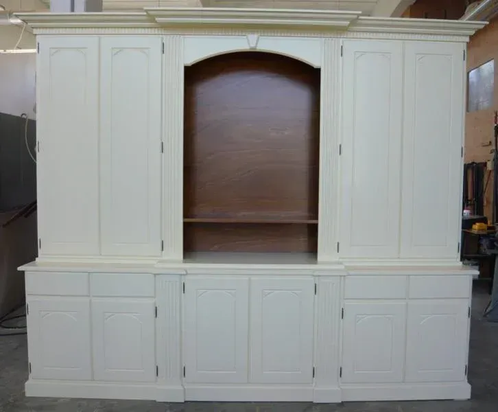 Mobile porta TV in legno color crema con mensola centrale ad arco e mobili contenitori inferiori.