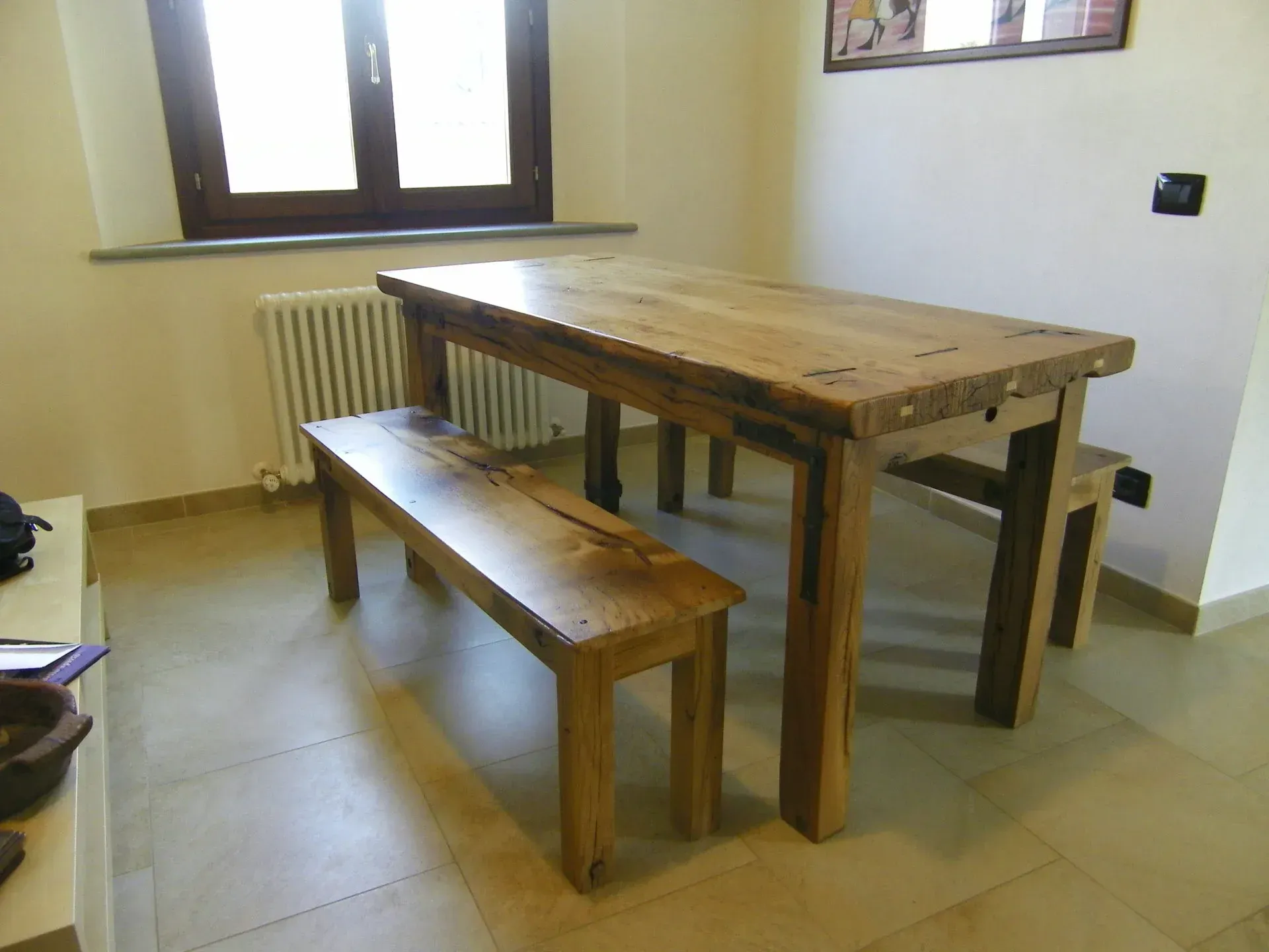 Tavolo da pranzo e panca in legno in una stanza con finestra e termosifone.