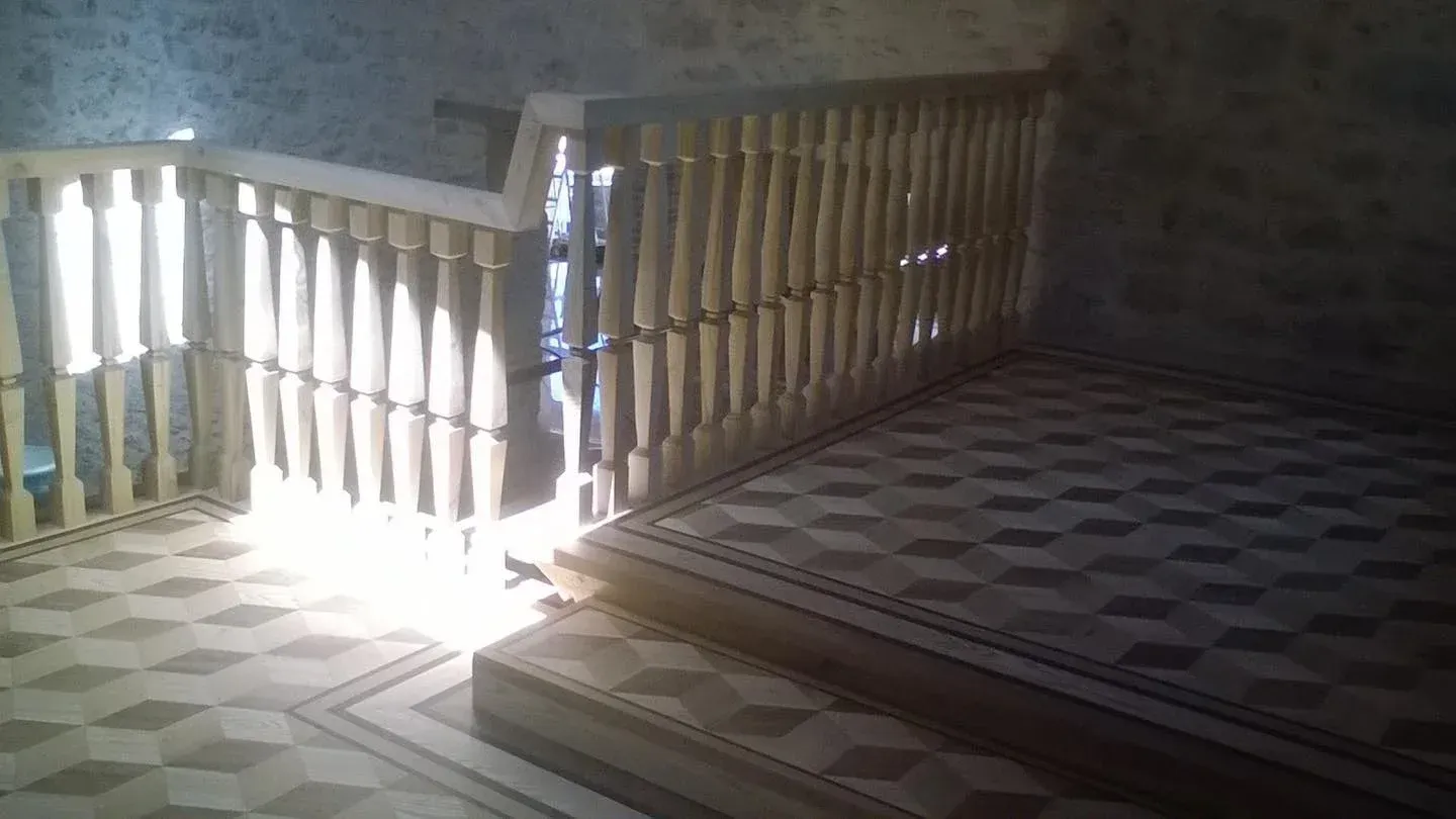 Scala con luce che filtra attraverso la ringhiera in legno sul pavimento decorato e sui gradini.