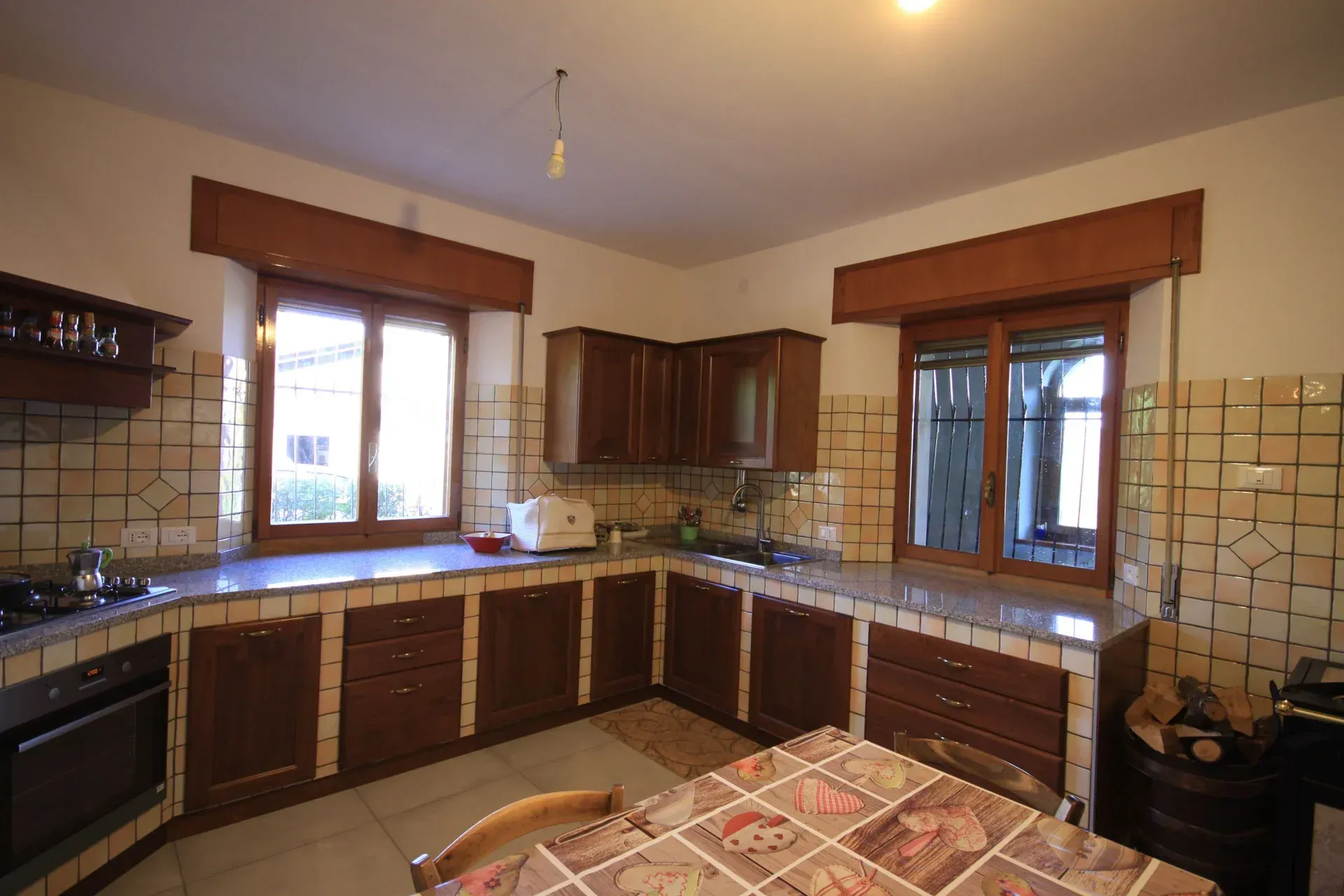 Cucina con mobili marroni, paraschizzi piastrellato e tavolo da pranzo.