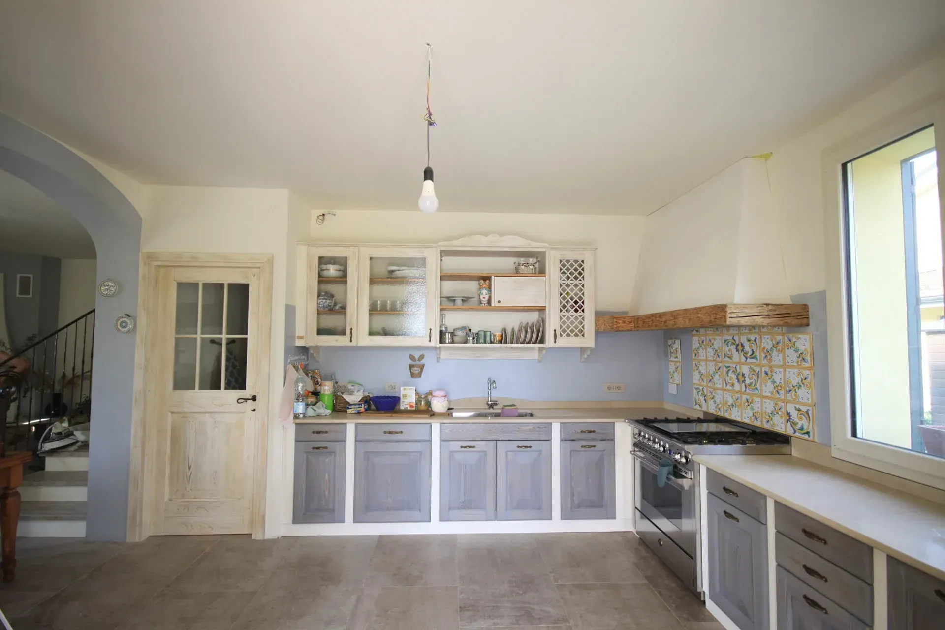 Cucina con mobili azzurri, dettagli in legno chiaro e paraschizzi in piastrelle blu.