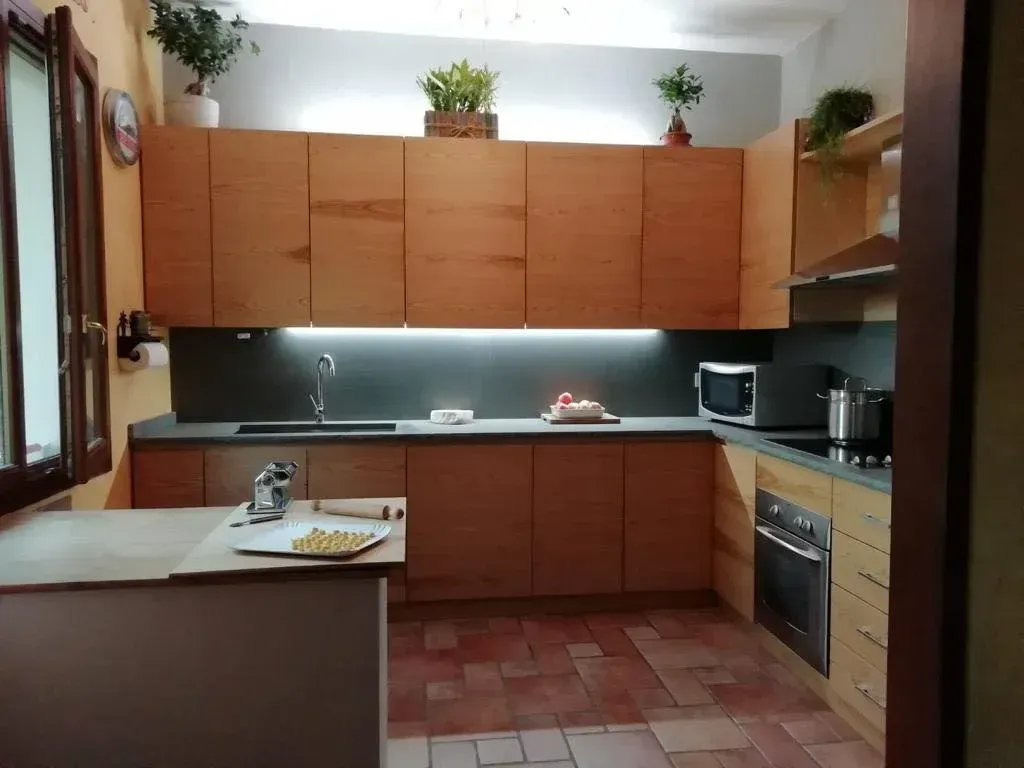 Cucina moderna con mobili in legno chiaro, ripiani grigi e piante.