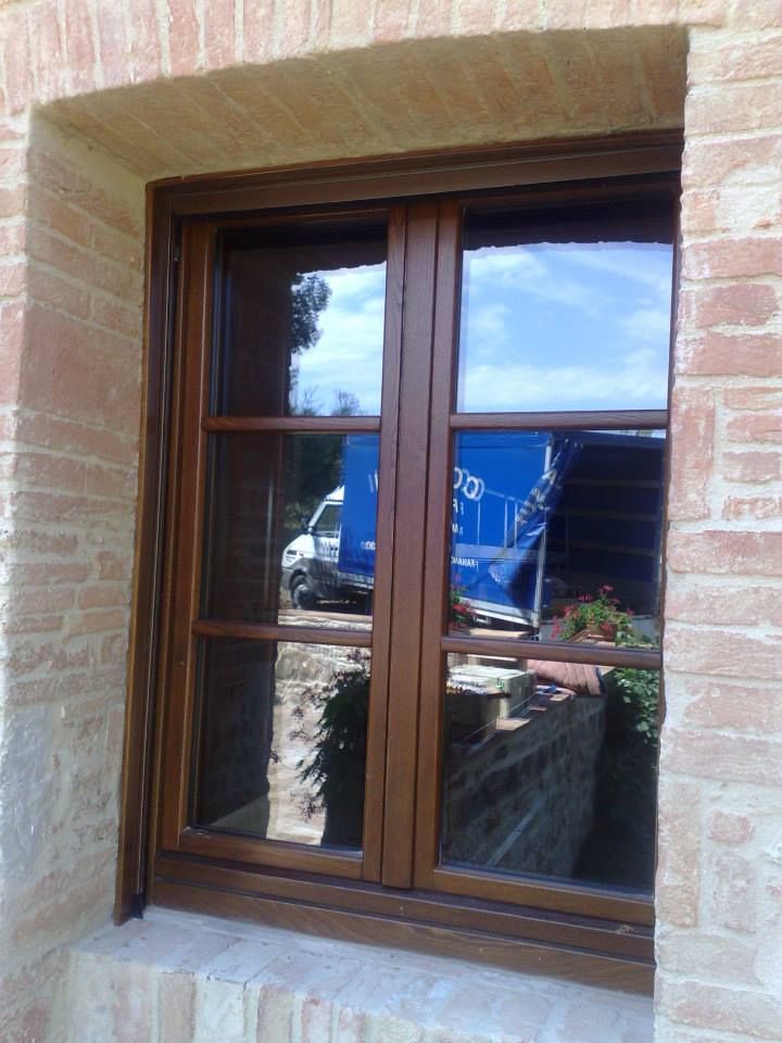 Finestra in legno marrone con cielo azzurro riflesso e camion in un edificio in mattoni.