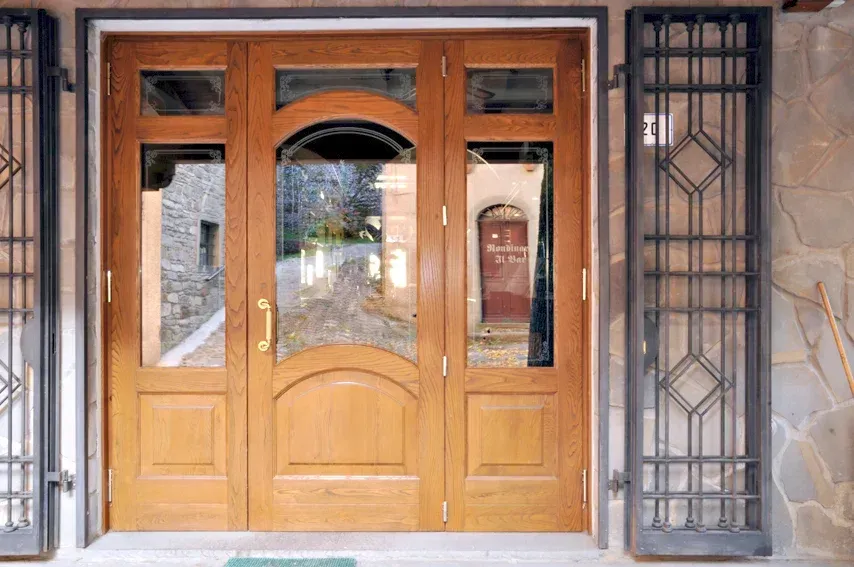 Porta d'ingresso in legno con pannelli in vetro e grate di sicurezza in metallo.