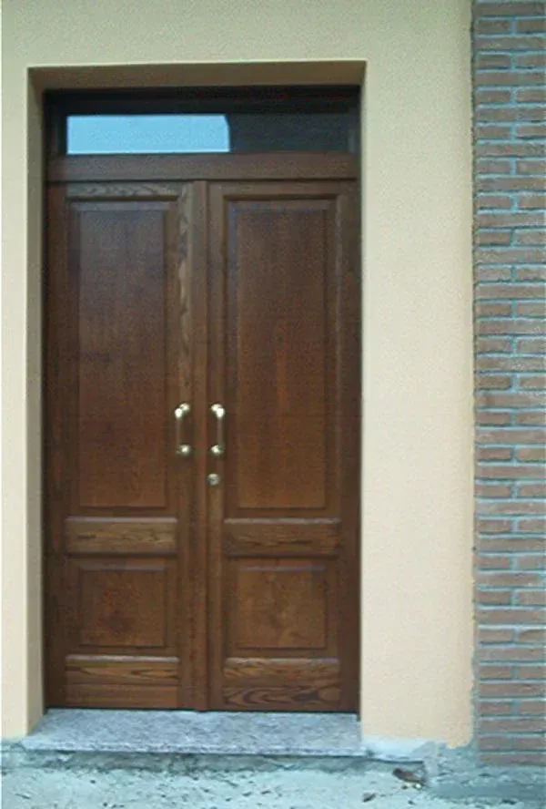 Doppie porte in legno con traverso in vetro, parete marrone chiaro e lato in mattoni.