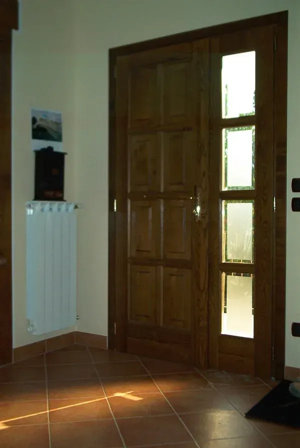 Porta in legno con pannelli in vetro; toni del marrone e del beige; luce del sole che filtra attraverso le finestre.