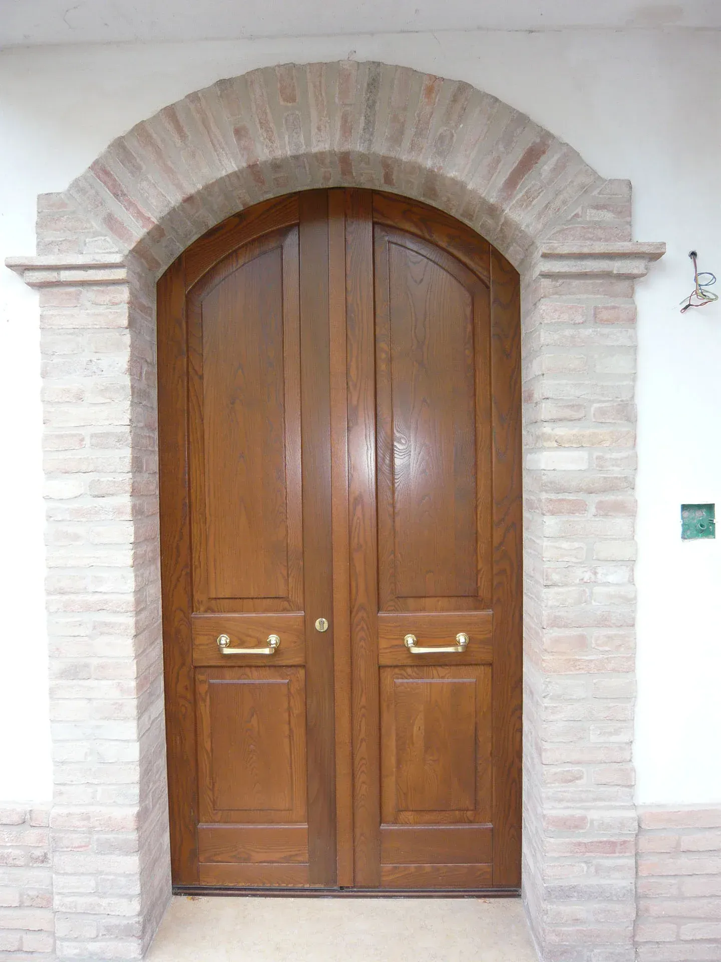 Doppie porte in legno con cornice in mattoni ad arco.