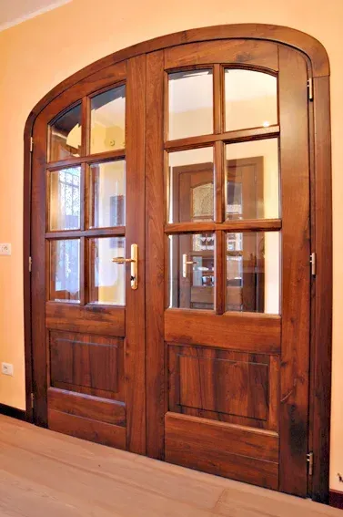 Doppie porte in legno con parte superiore arcuata e pannelli in vetro.