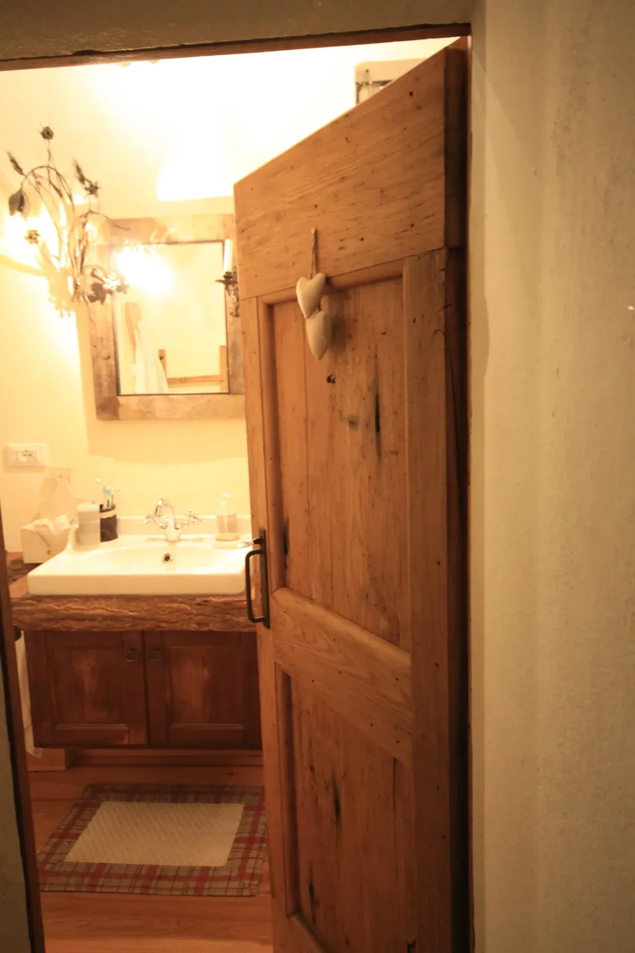 Porta del bagno in legno parzialmente aperta, che rivela un mobiletto con specchio.