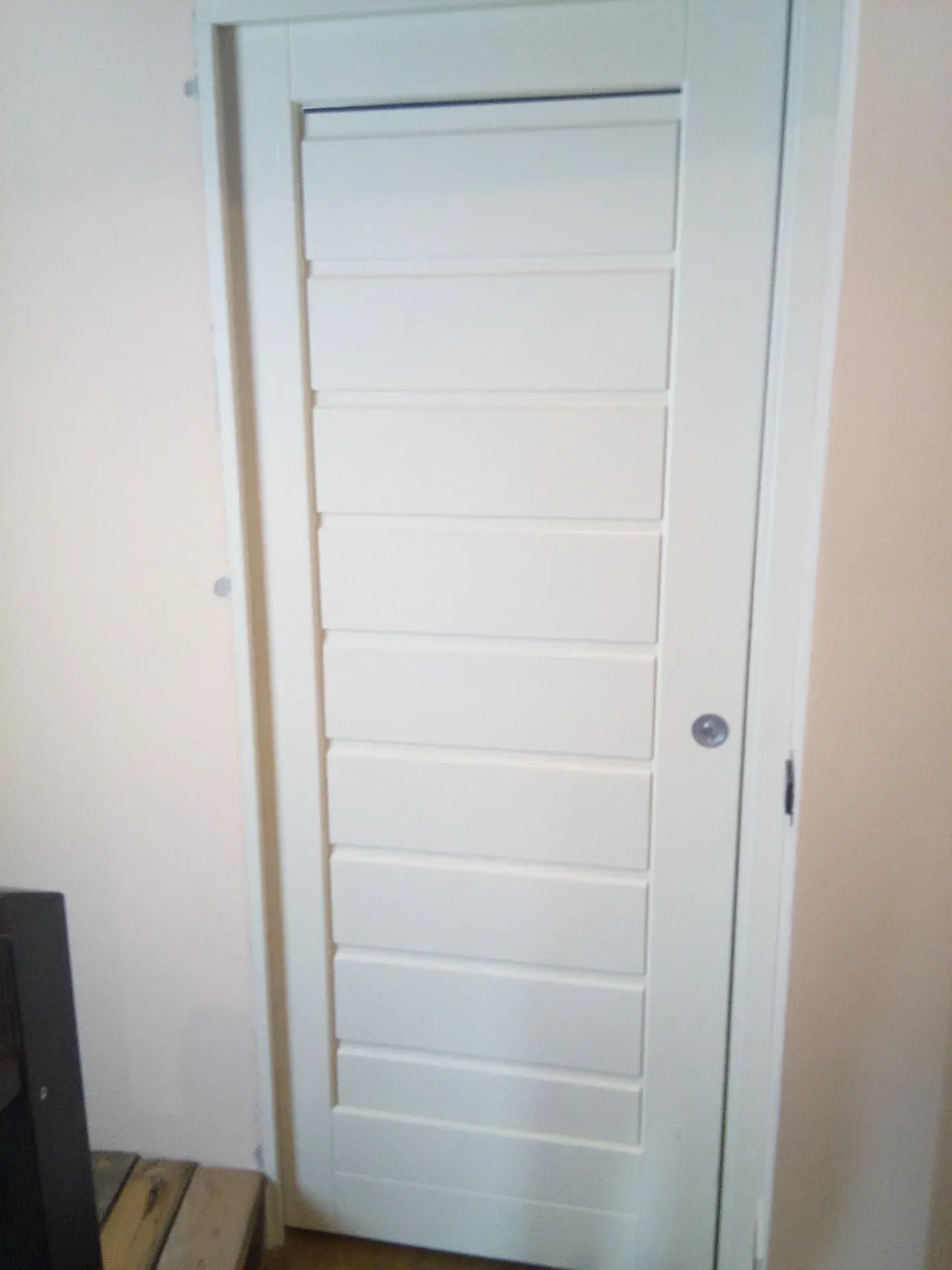 Porta interna bianca con pannelli rettangolari orizzontali, inserita in una parete di colore chiaro.