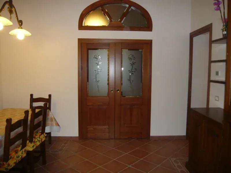 Doppie porte in legno con pannelli in vetro smerigliato, sormontate da una finestra ad arco