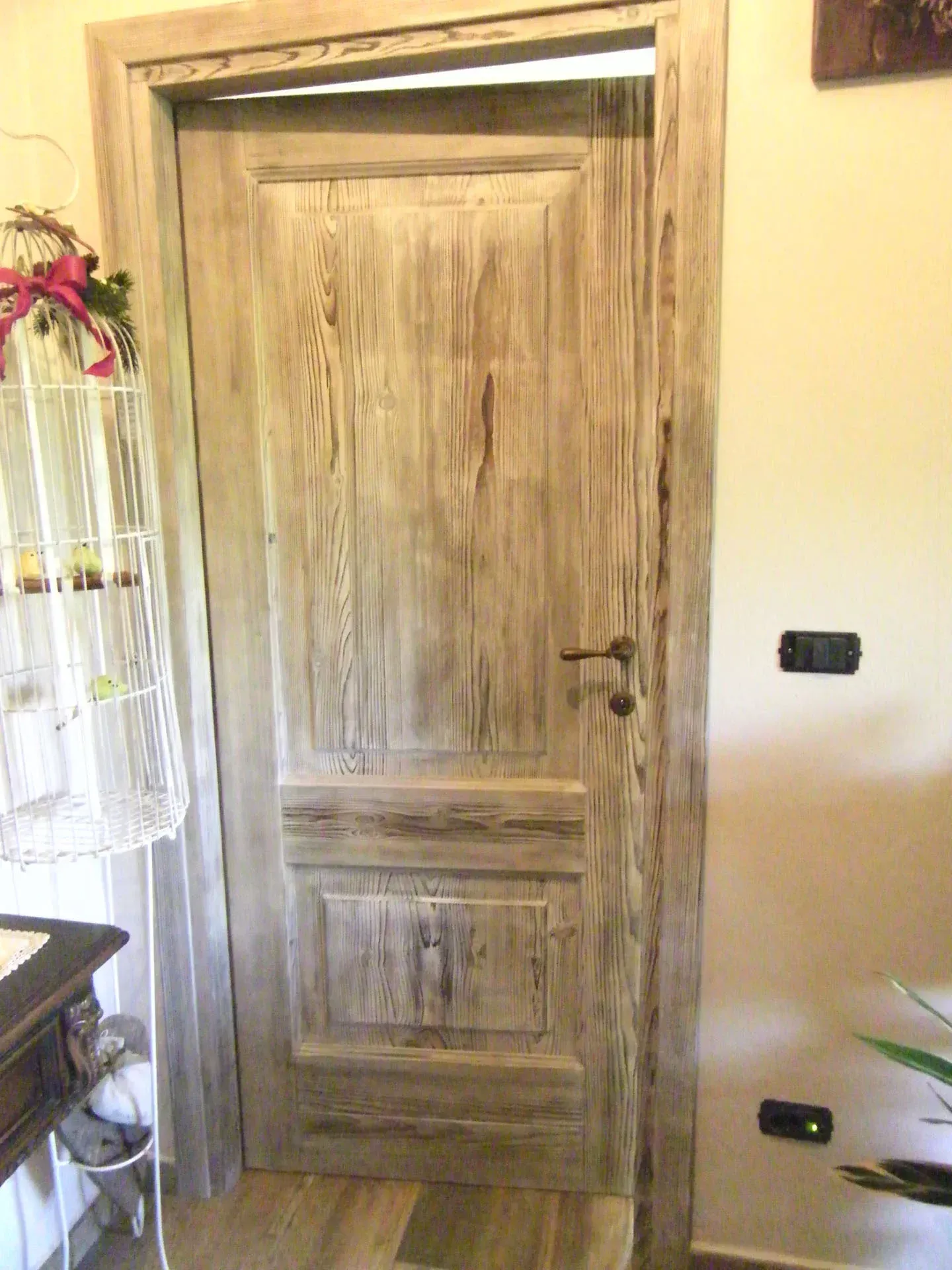 Porta di legno con vernice invecchiata, all'interno di una stanza.