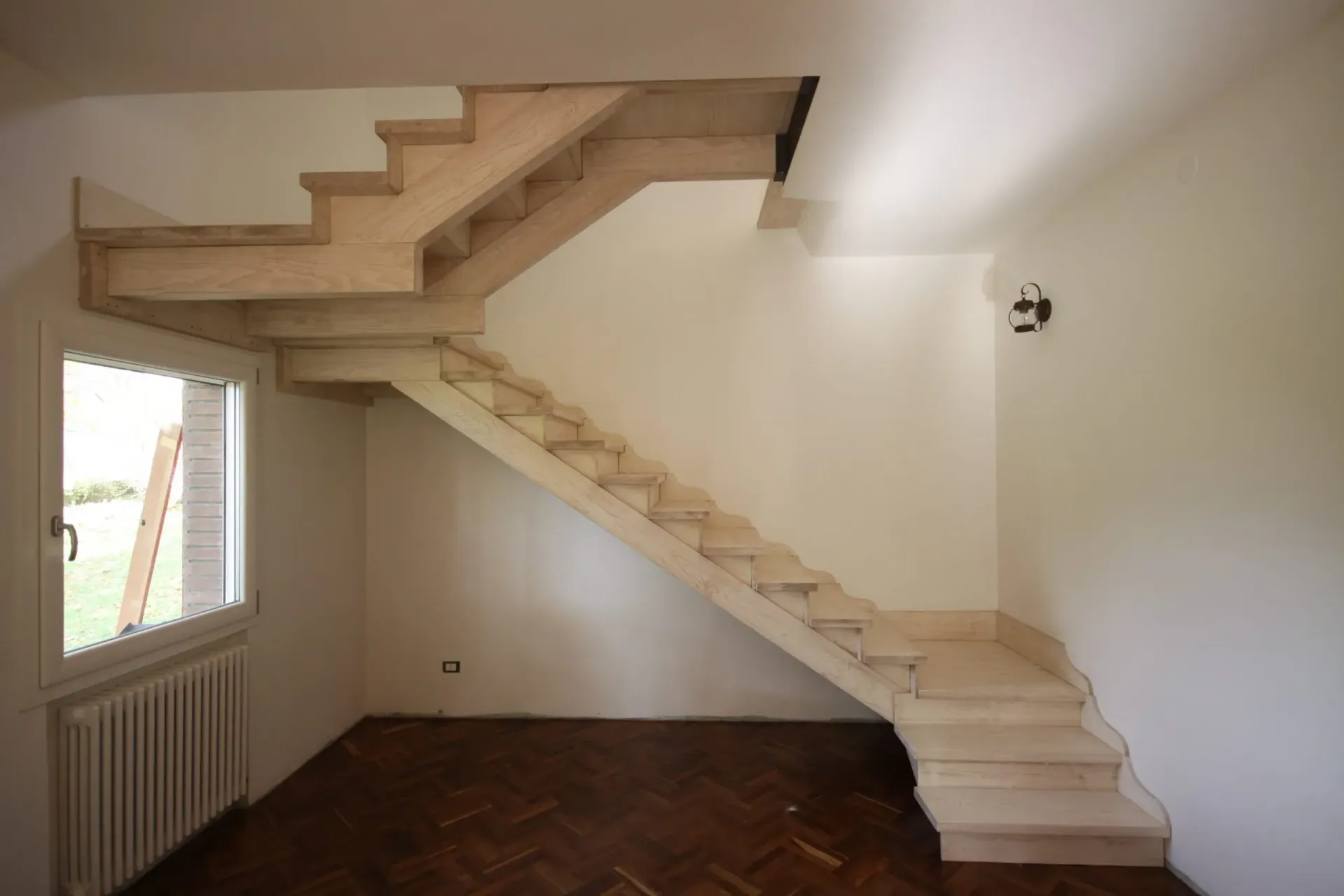 Scala con gradini in marmo in una stanza con finestra e pavimento in legno.