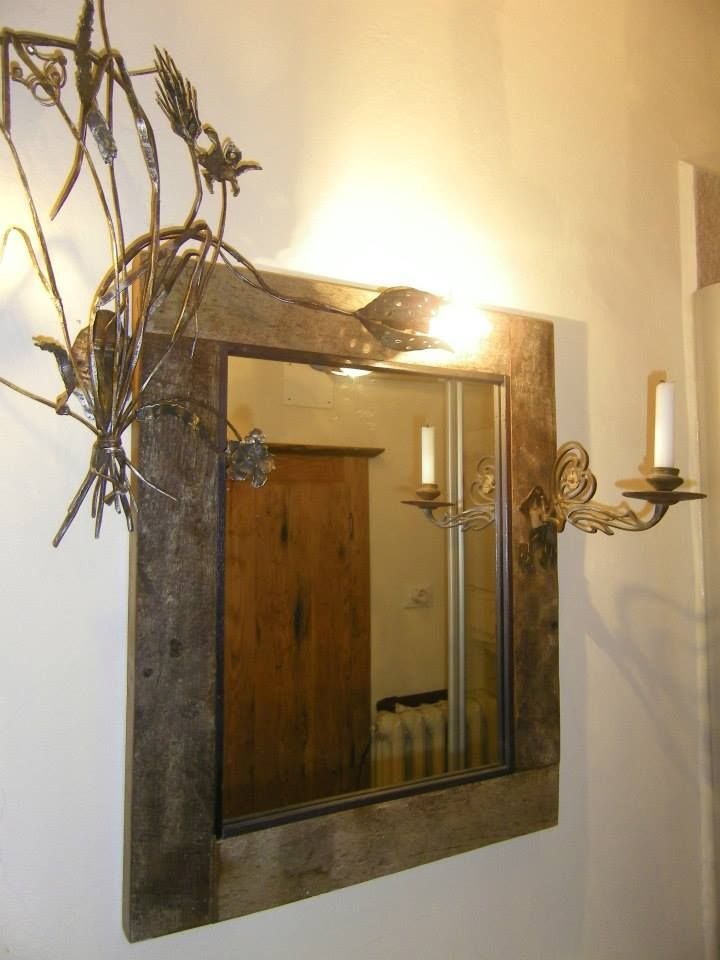 Specchio con cornice in legno rustico, applique in metallo e porta in legno riflettente.