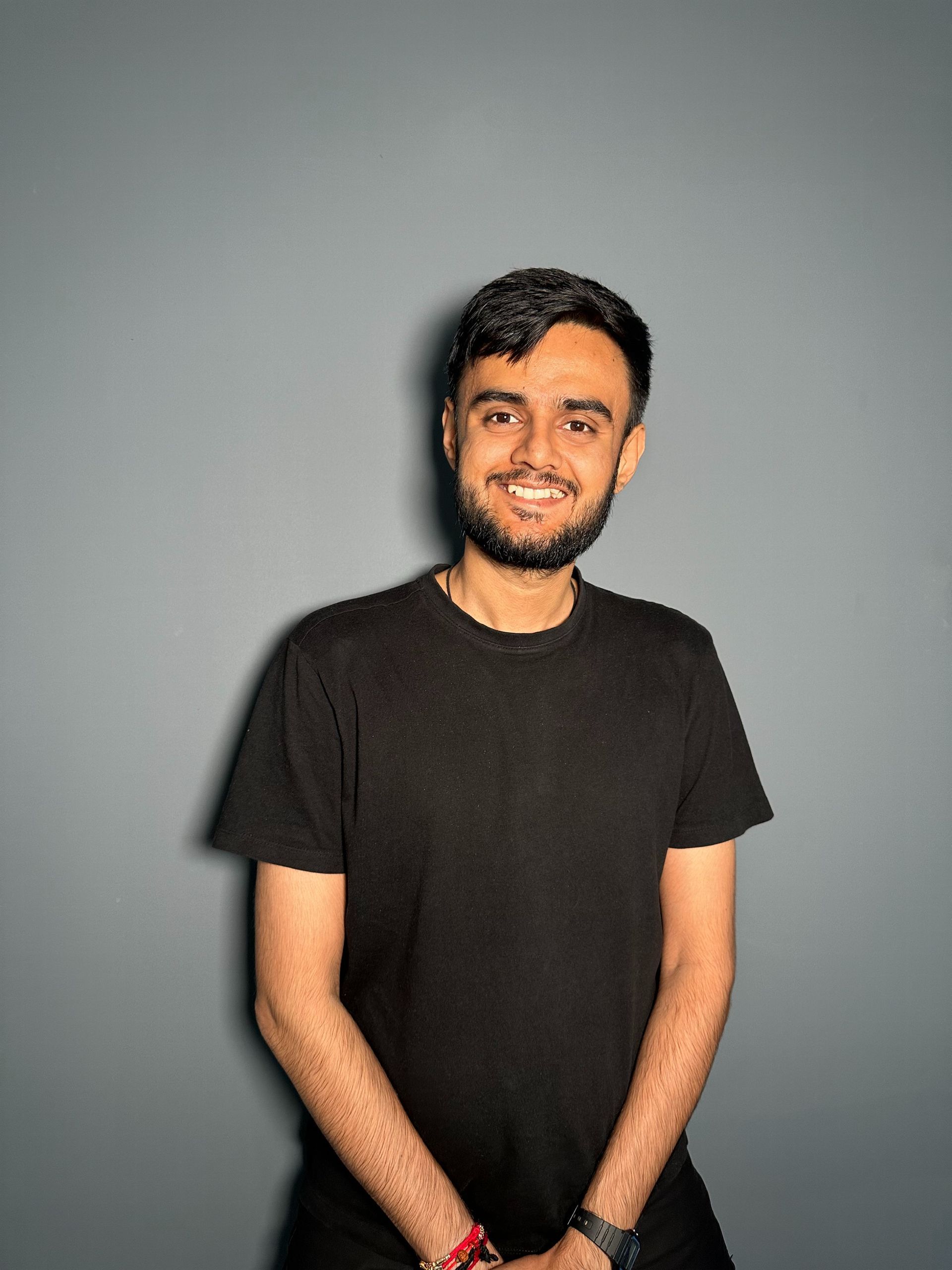 A man with a beard is wearing a black shirt and smiling.