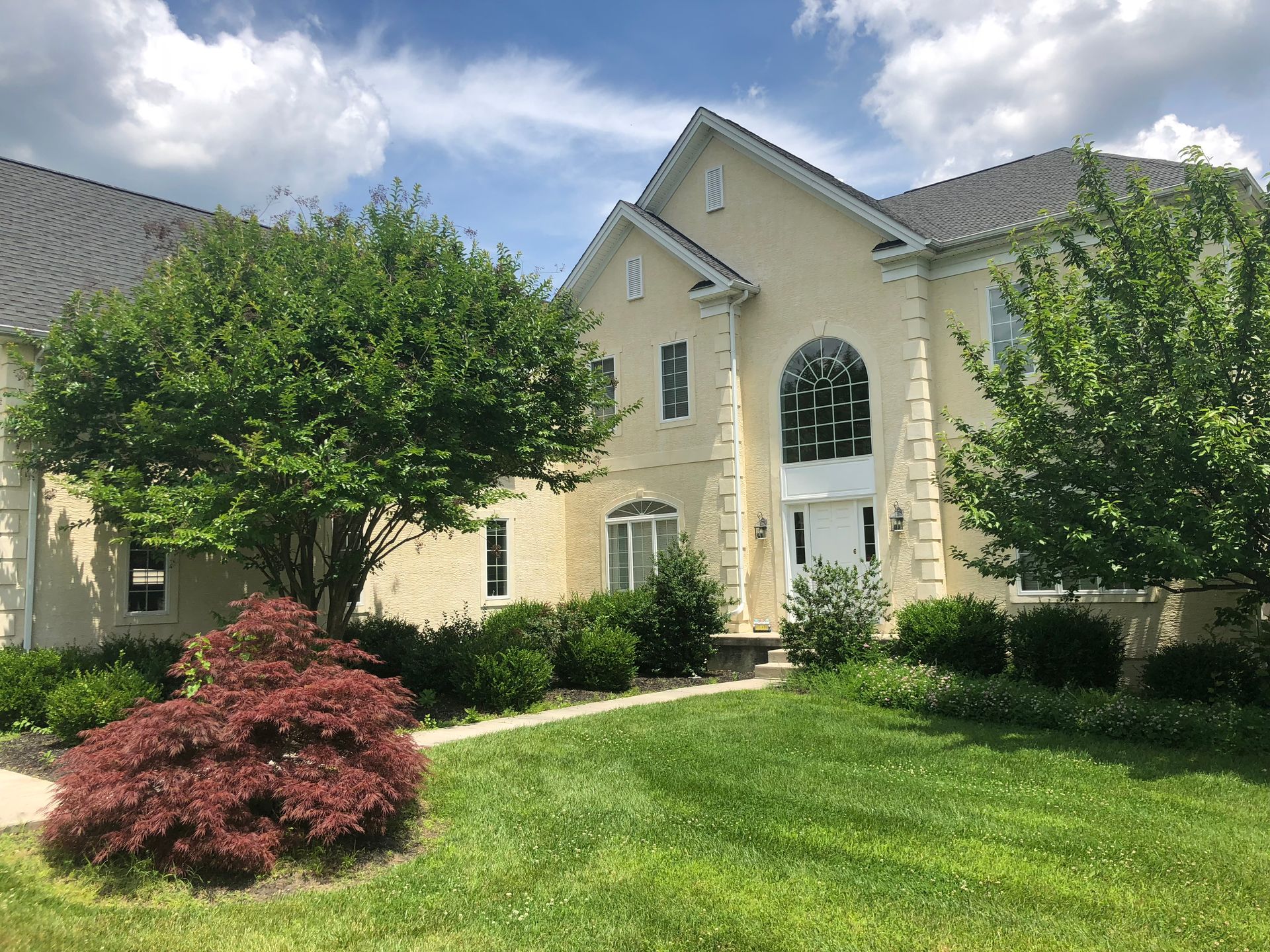 Construction worker on scaffolding, building a multi-story house on a sunny day.