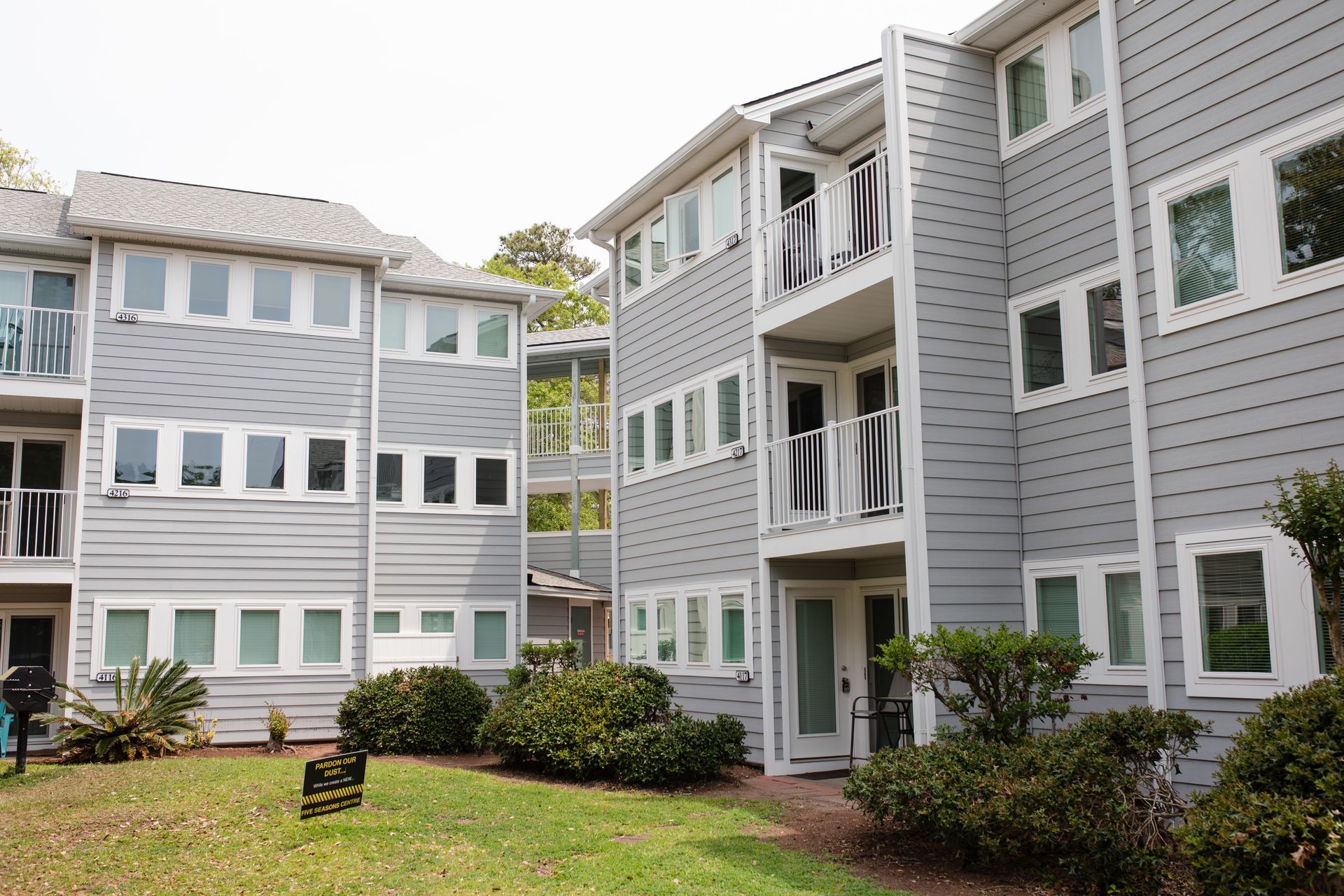 Multi-story building with white, tan, and brown siding; a garage; and snow-covered ground.