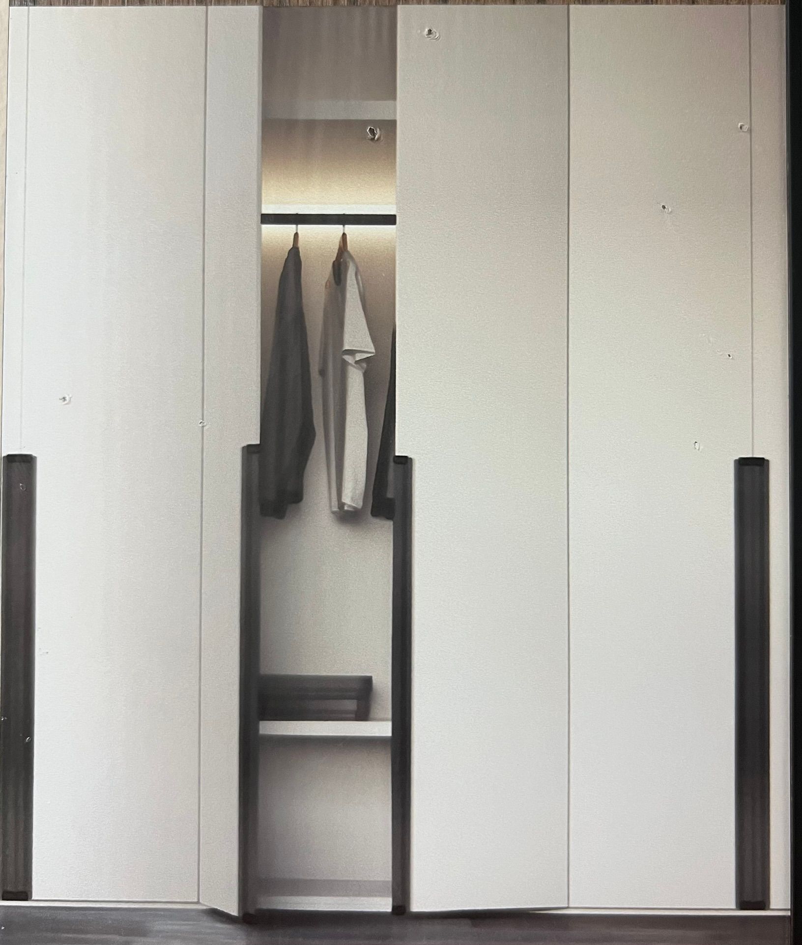 A wardrobe with the doors open and clothes hanging in it