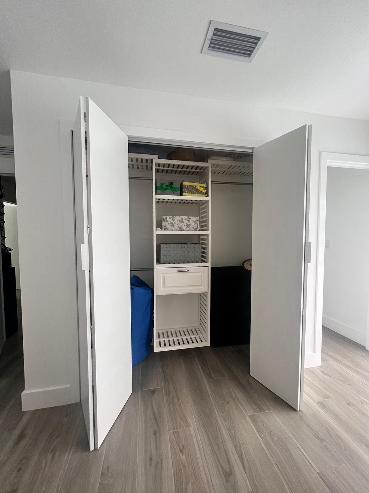 A closet with the doors open and shelves and drawers