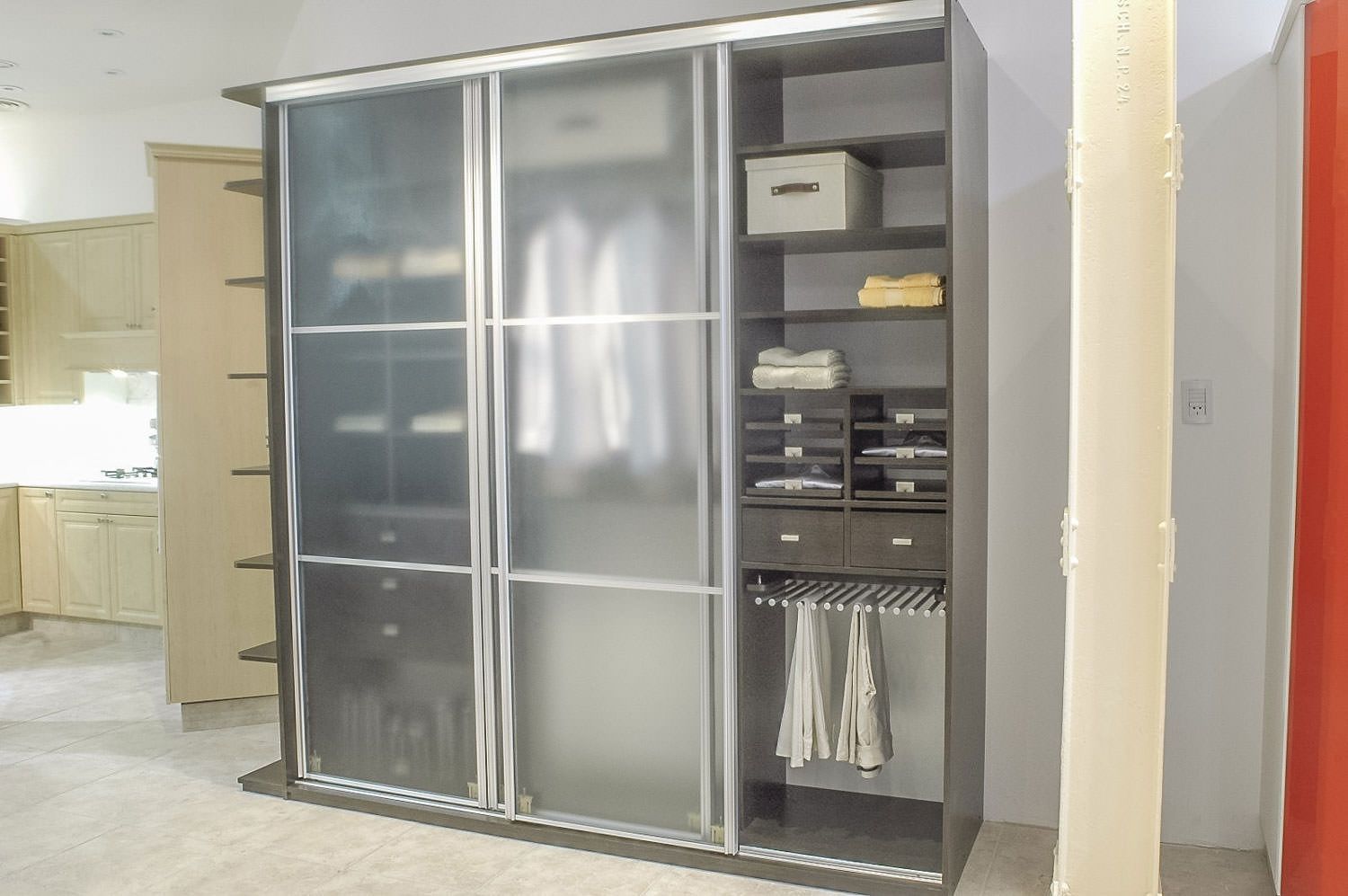 A closet with sliding glass doors filled with clothes