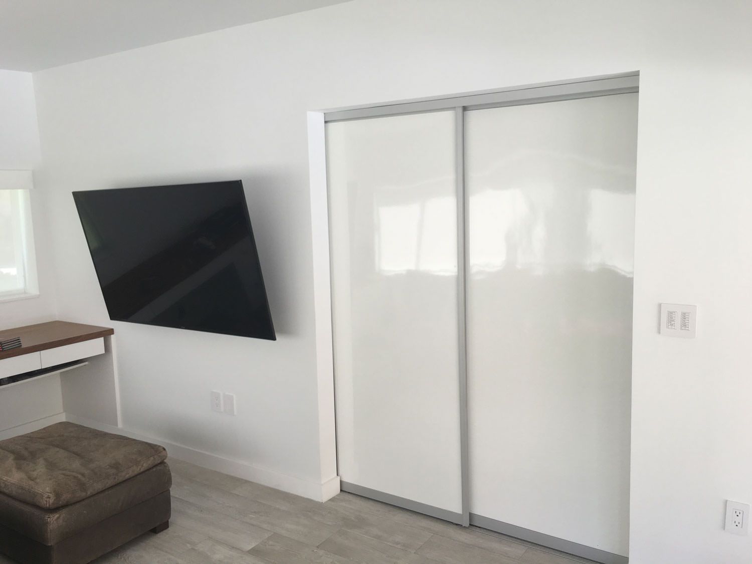 A bedroom with a flat screen tv mounted on the wall.