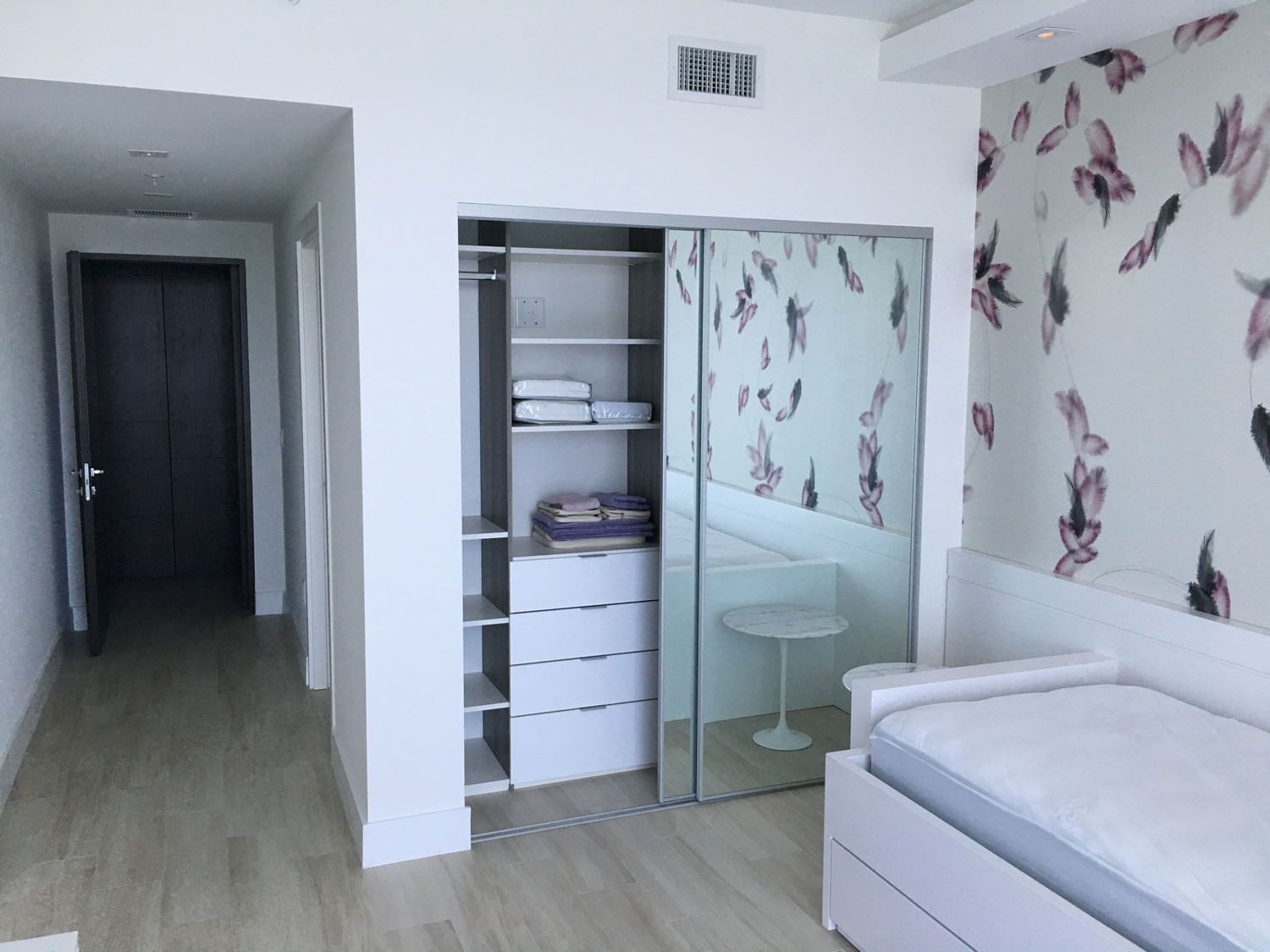 A bedroom with a bed and a closet with sliding glass doors