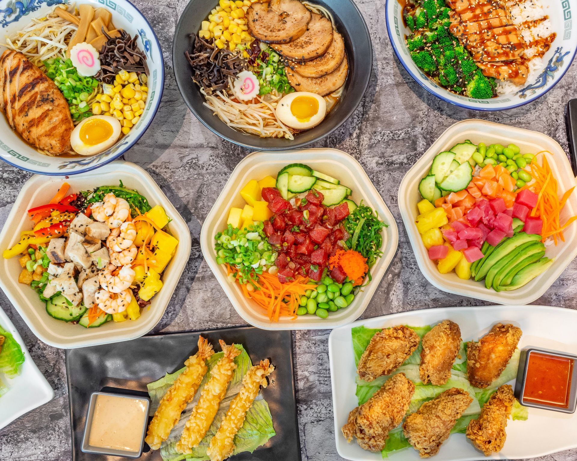 Poke Go's 3 ramens, 3 poke bowls, shrimp tempura, and fried chicken wings on a grey table surface.