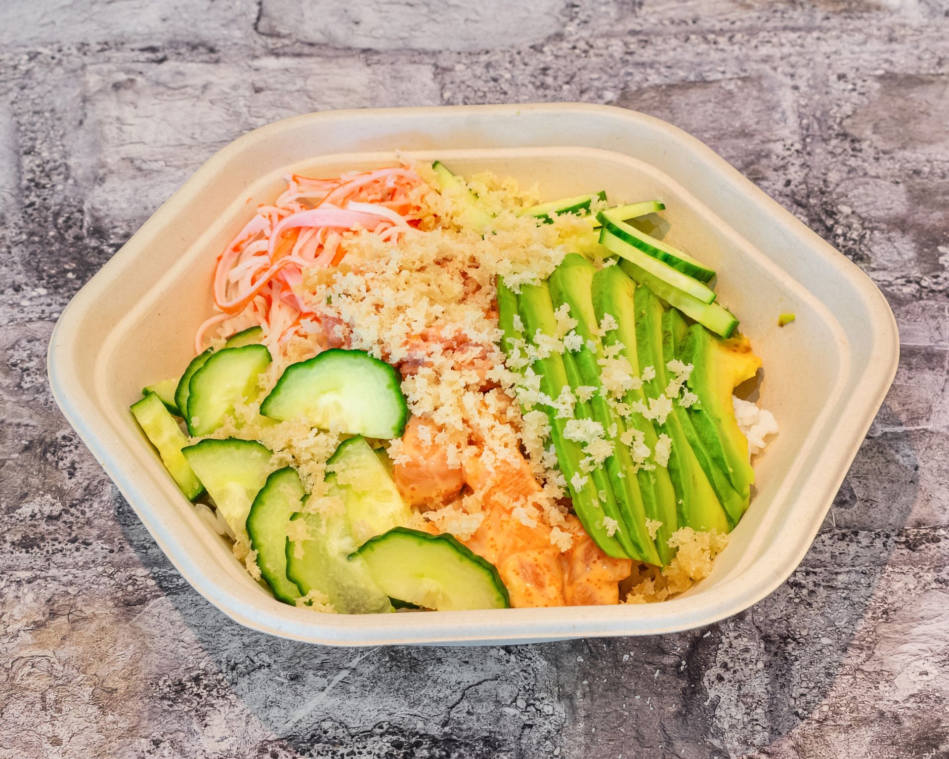 Poke Go's poke bowl on table, with cucumber slices, avocado slices, tempura flakes, crab sticks, and tempura flakes