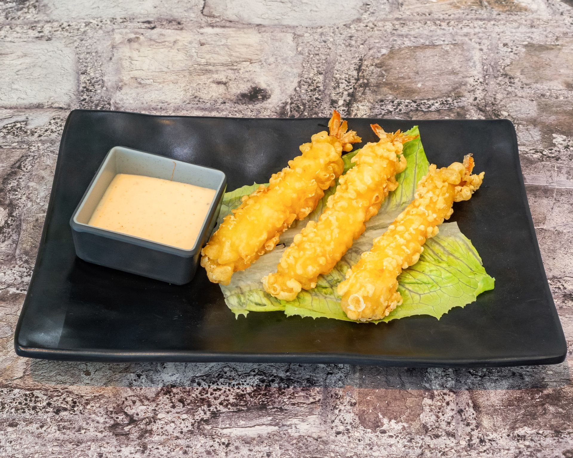 Poke Go's shrimp tempura in a black dish on table.