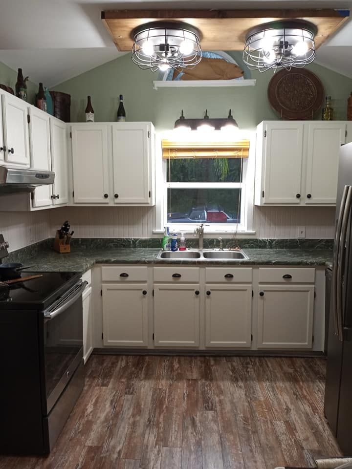 Kitchen with white cabinets, green countertops, and a window above the sink.