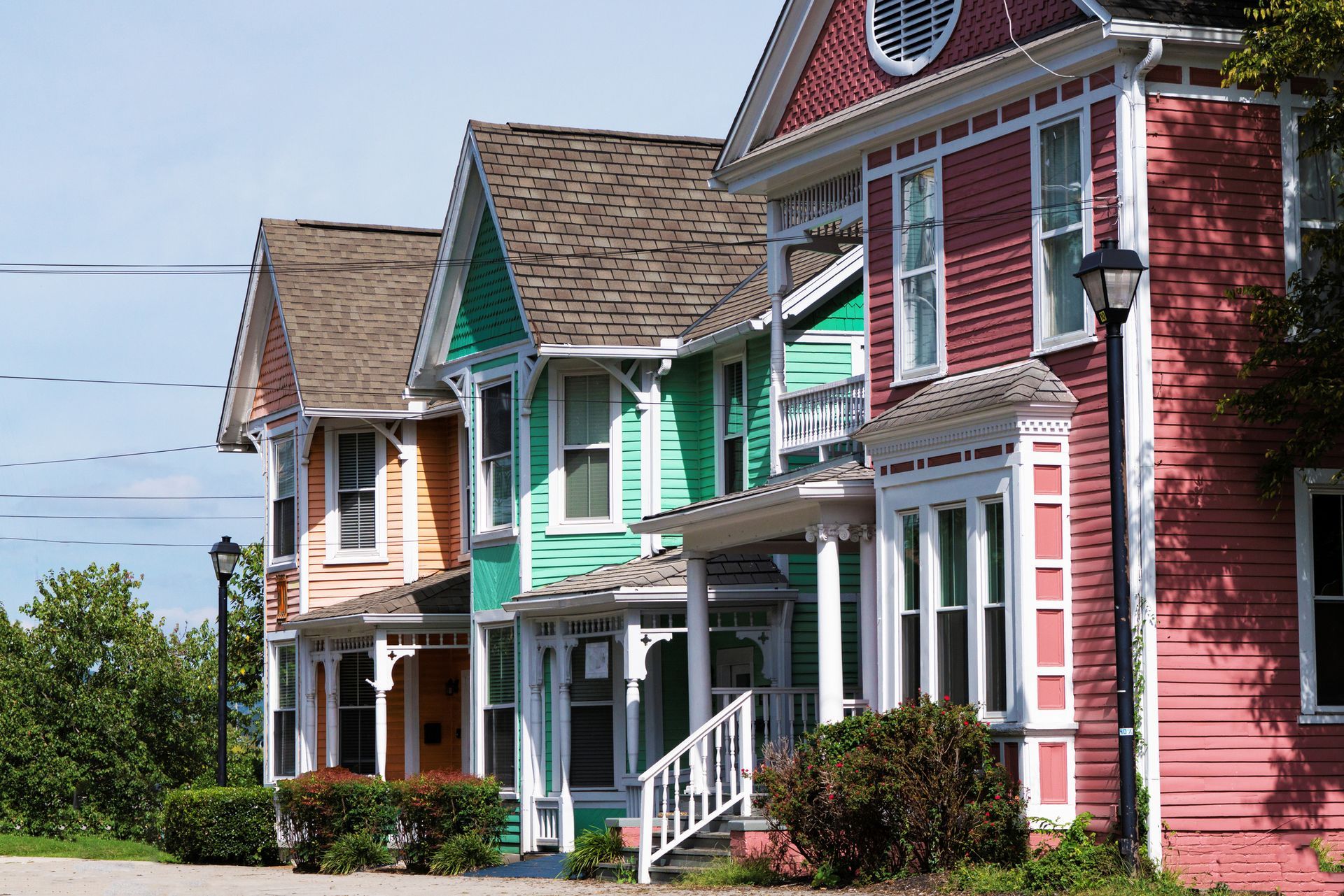 Row of colorful Victorian houses in shades of peach, green, and red with white trim.