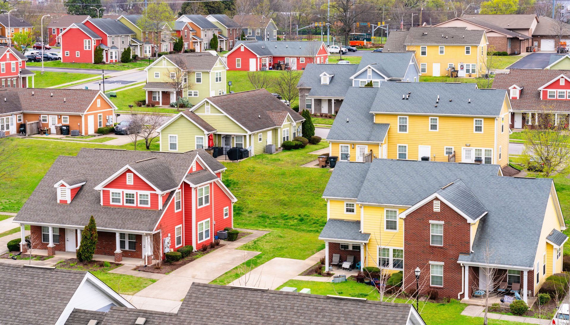 Colorful houses in a suburban neighborhood on a grassy hill.
