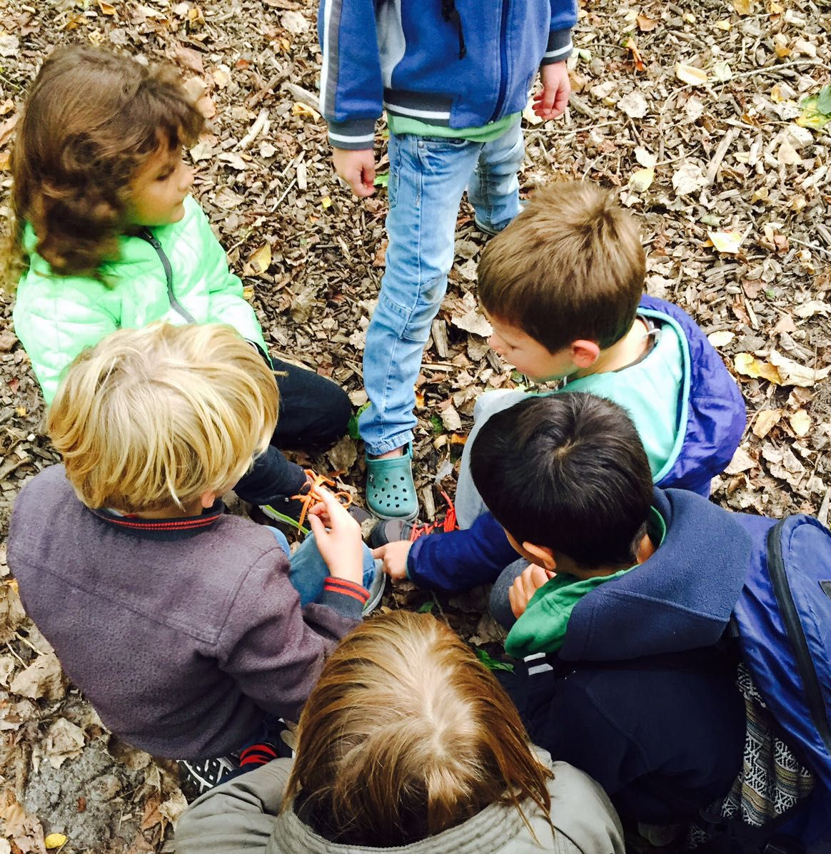 Kinderen in een groepje bij elkaar buiten onderzoek doen.