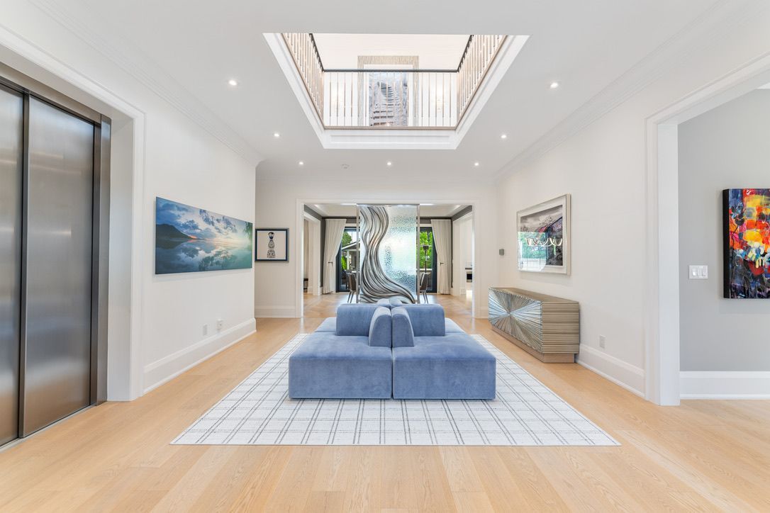 Bright modern lobby with blue double doors, patterned floor, tall windows, and staircase railing