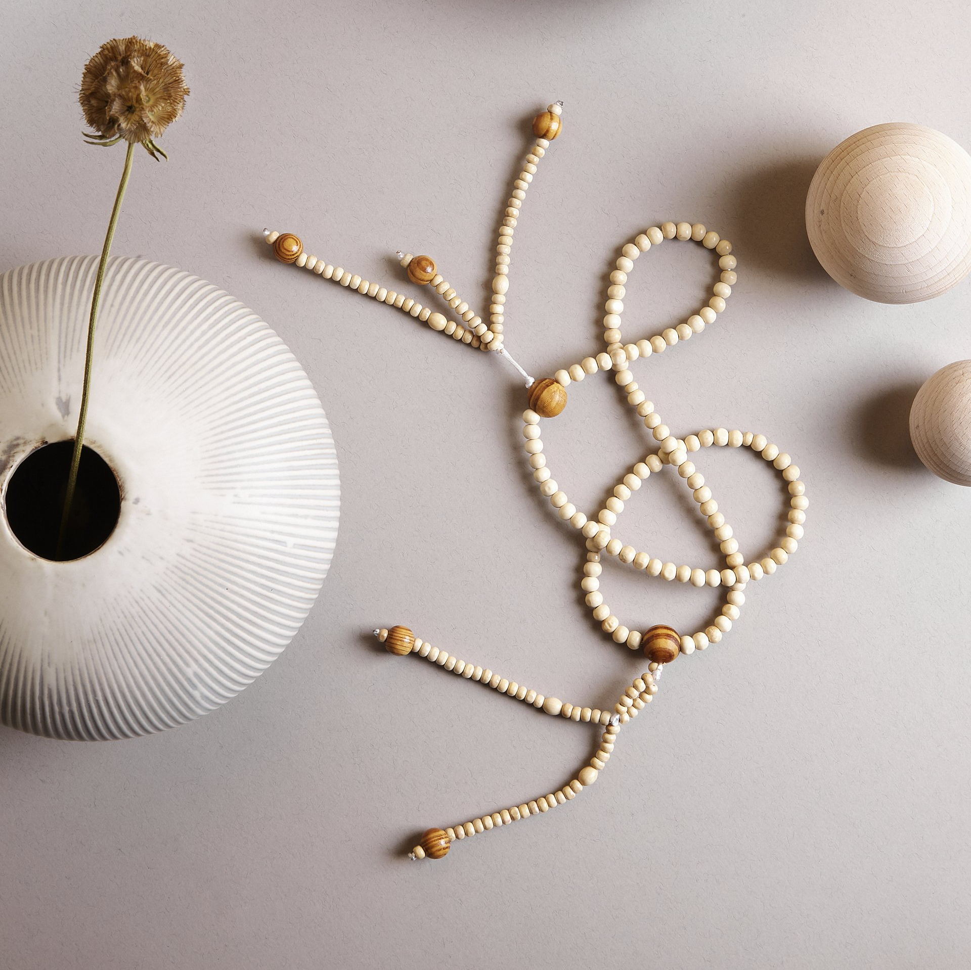 Un vaso bianco con un fiore dentro e una collana di perline