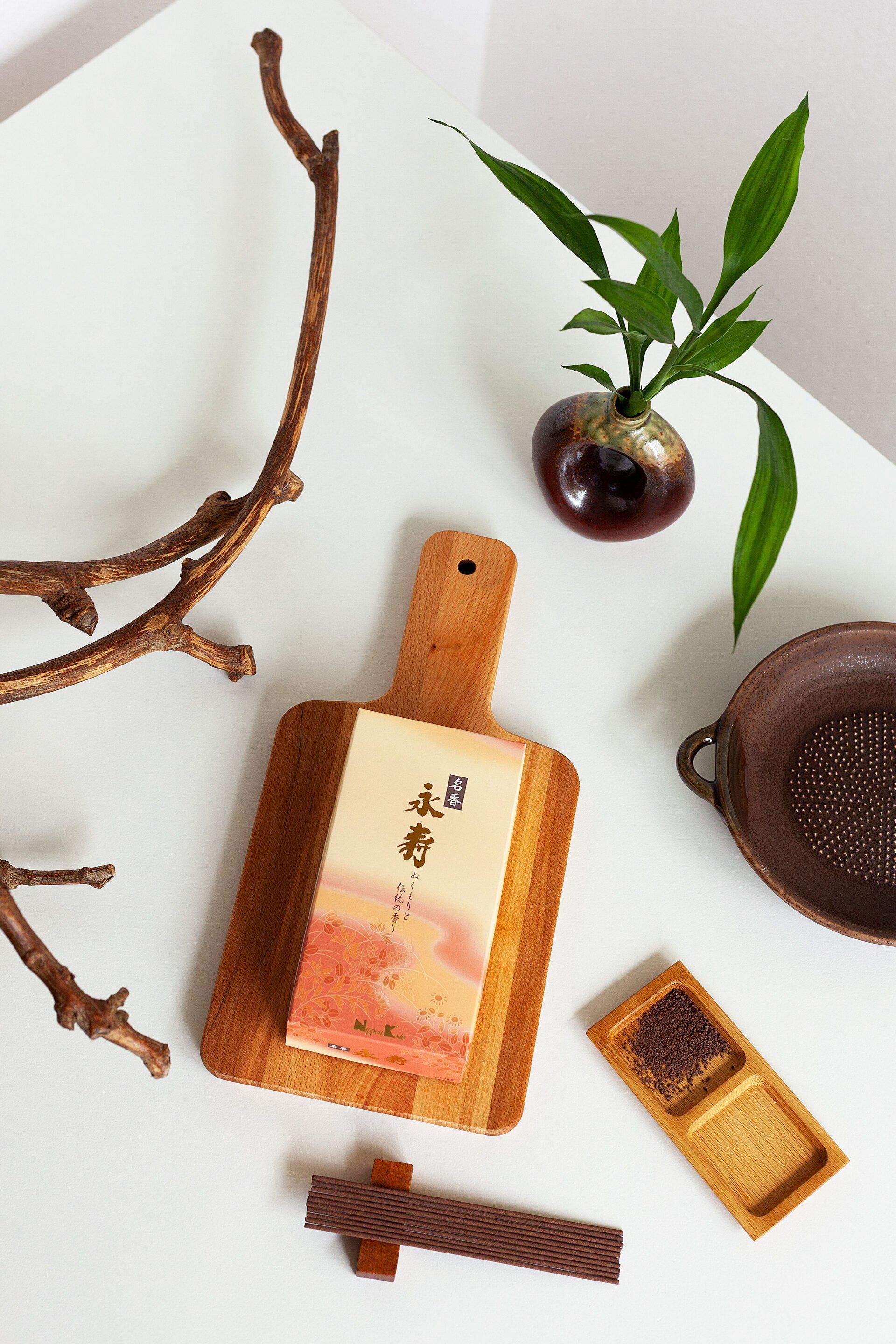 Un tagliere di legno è su un tavolo accanto a una pianta