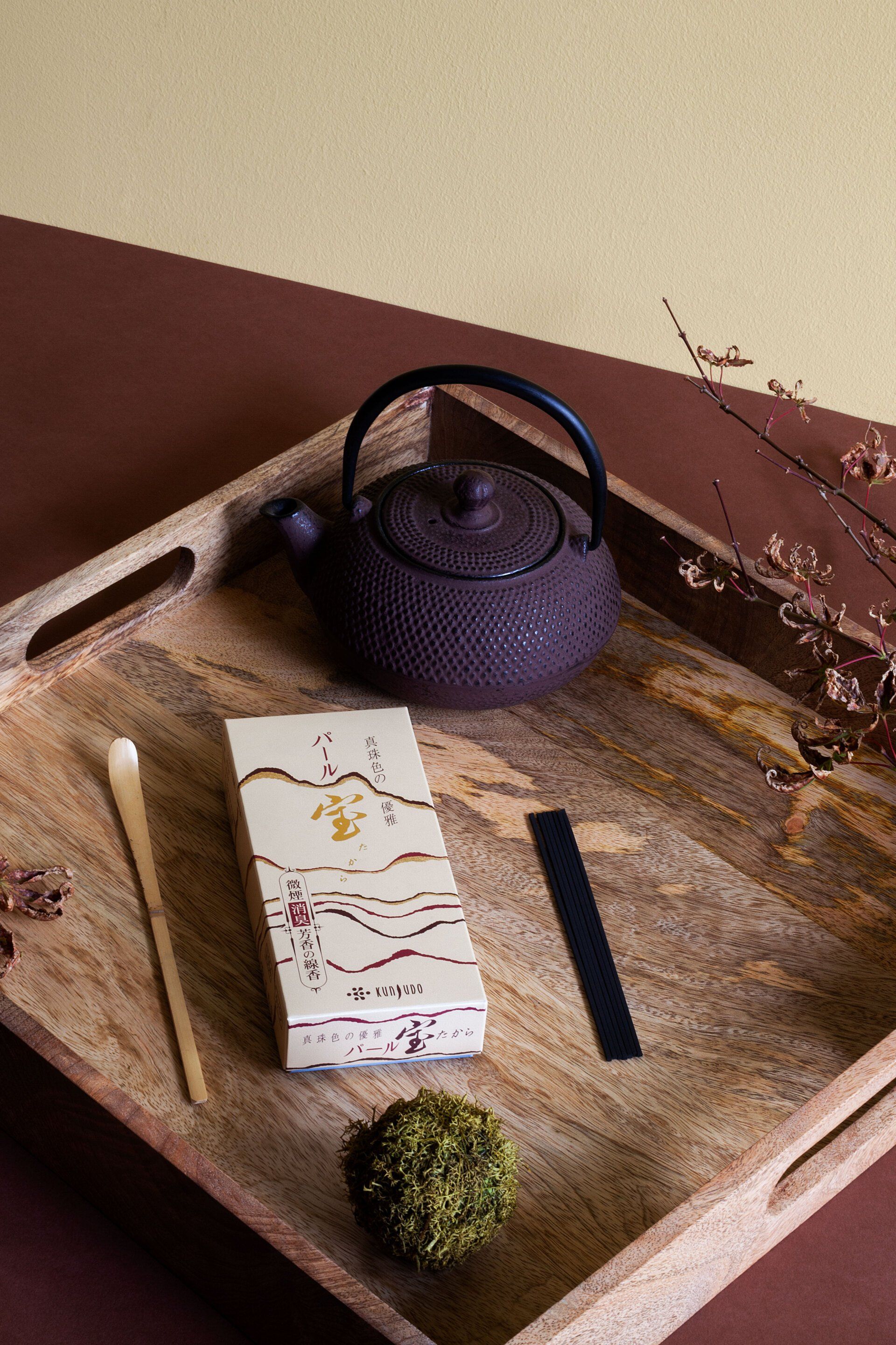 Un vassoio di legno con una teiera, una scatola di incenso e un cucchiaio sopra.