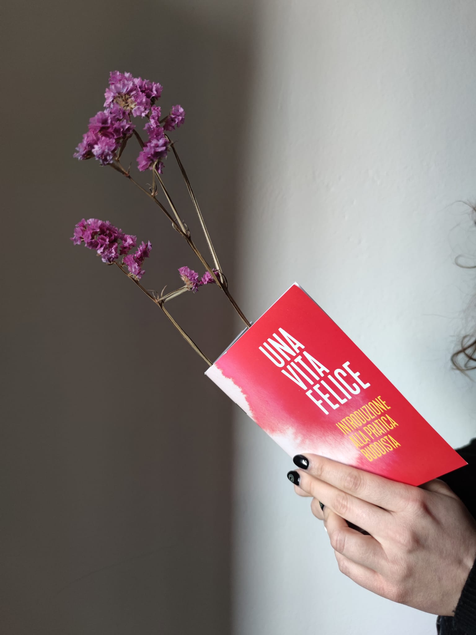 Una donna tiene in mano un libro con dei fiori viola.