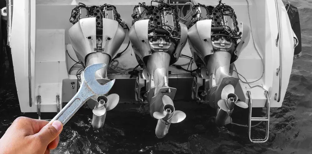 A Hand Holding a Wrench, Working on Three Boat Motors at The Back of A Boat — HiTune Marine In Port Douglas, QLD 