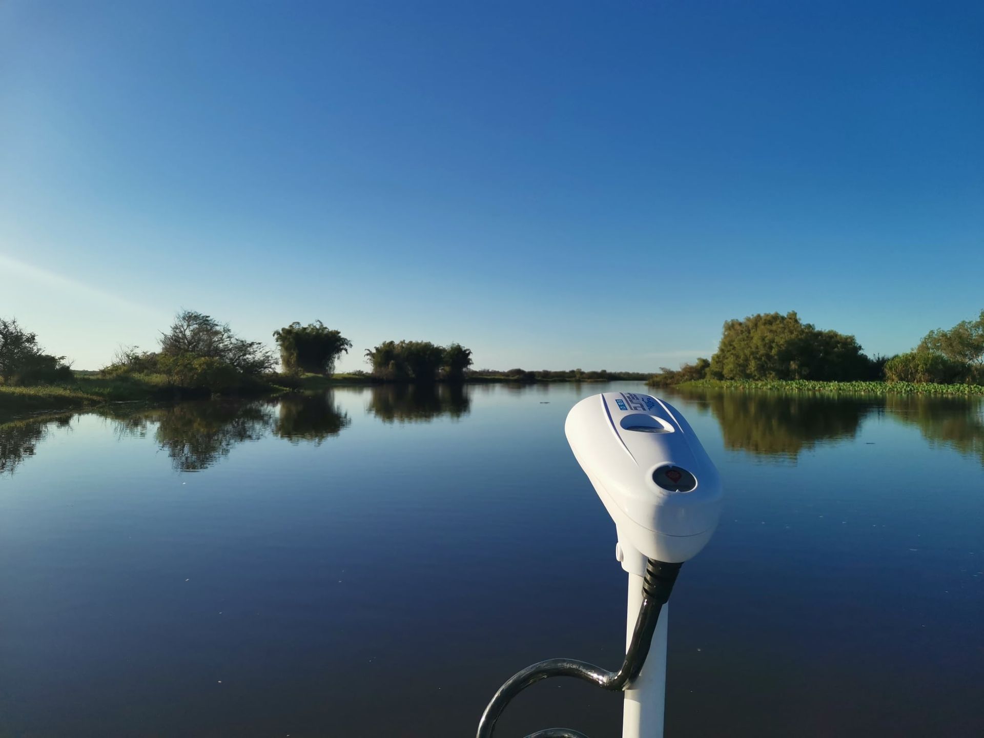 Boat on A Calm, Dark River Under a Clear Blue Sky, with Trees Lining the Banks — HiTune Marine In Innisfail, QLD 
