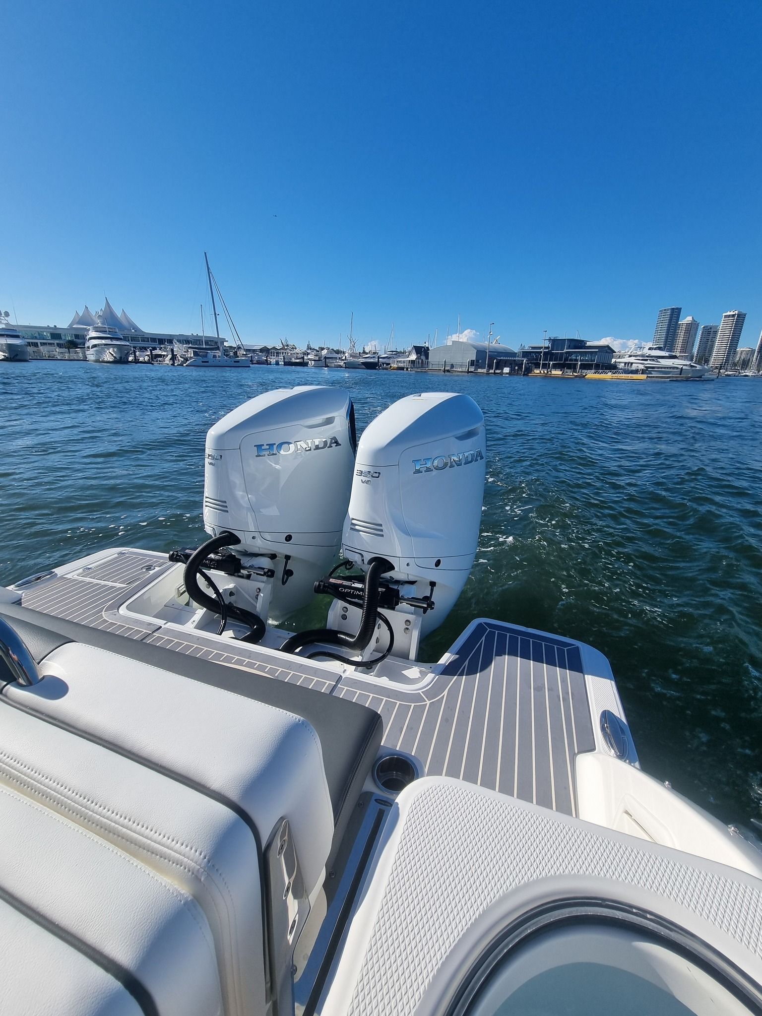 Two White Outboard Boat Motors on A Boat, Sailing on Water with A City Skyline in The Background — HiTune Marine In Mossman, QLD 