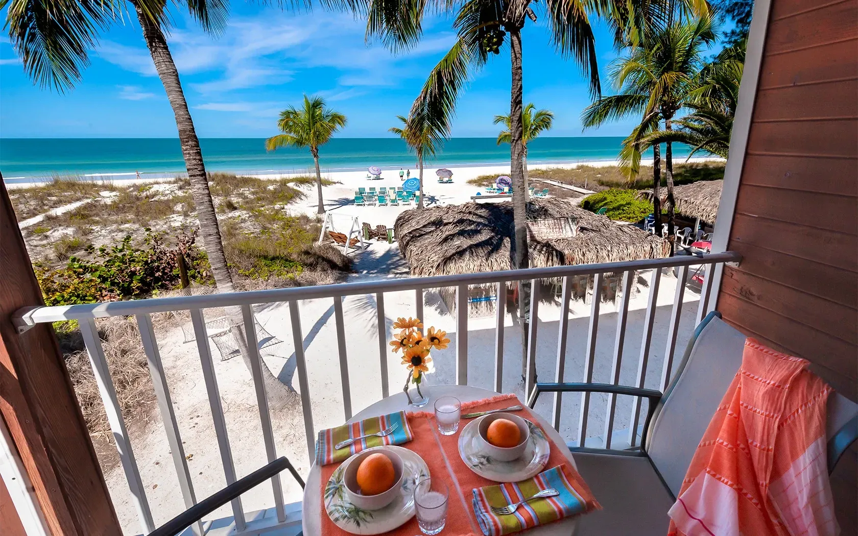 A balcony with a table and chairs overlooking the ocean.