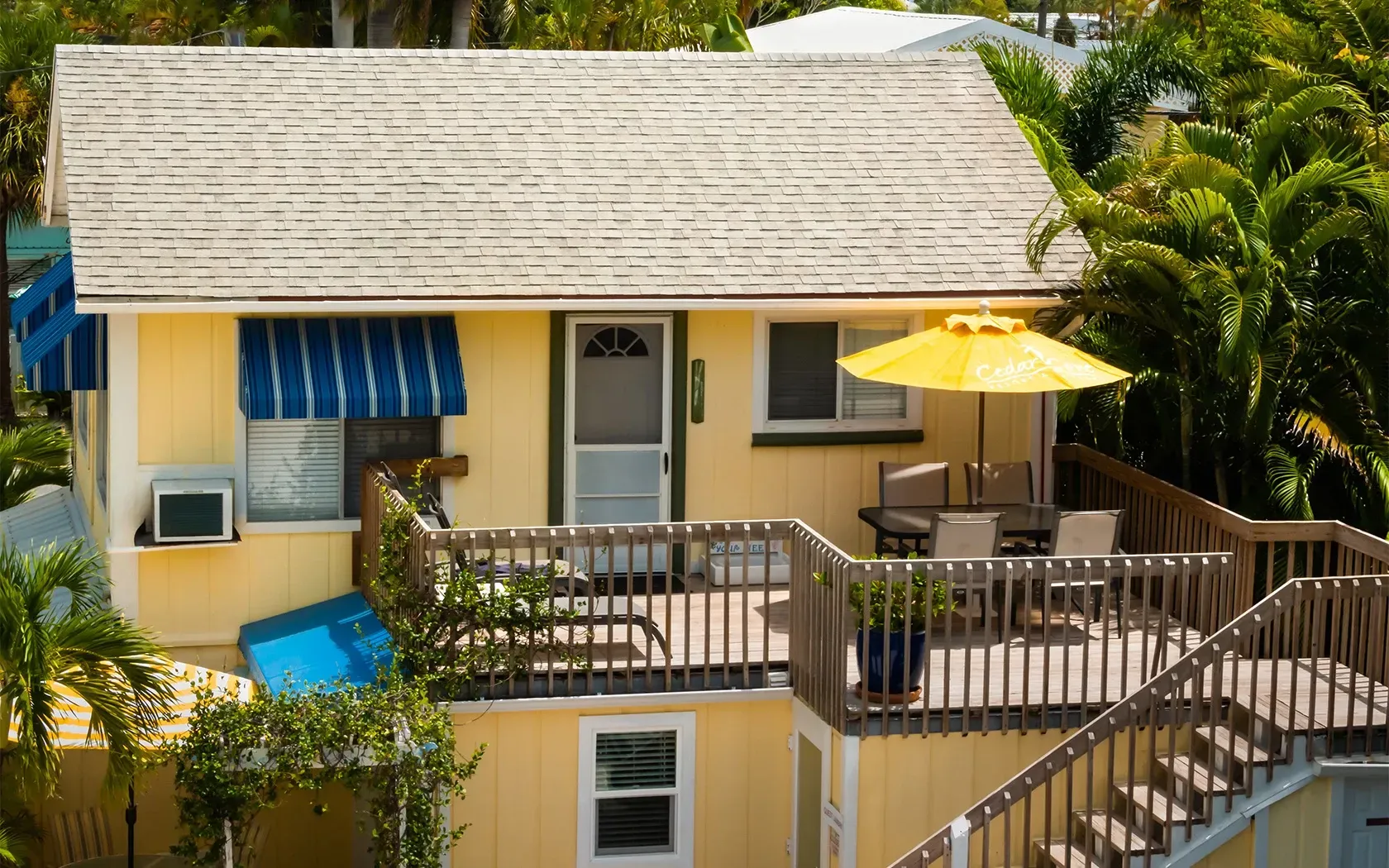 A small yellow house with a deck and stairs