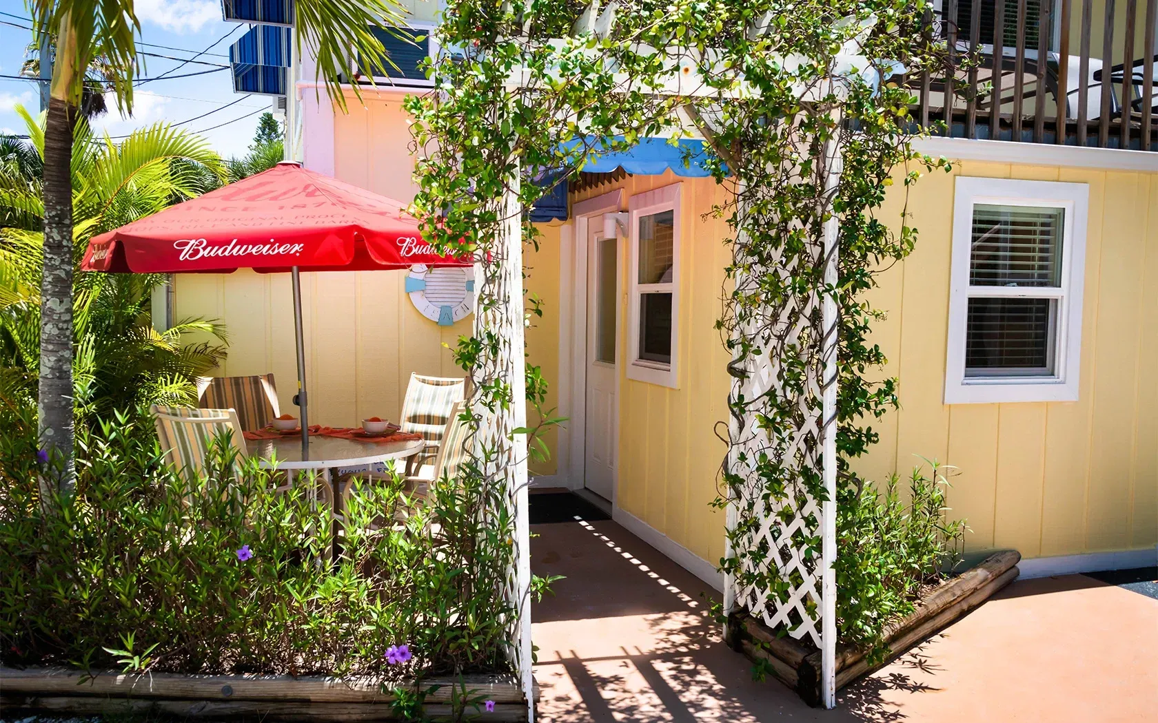 A yellow house with a red umbrella that says budweiser