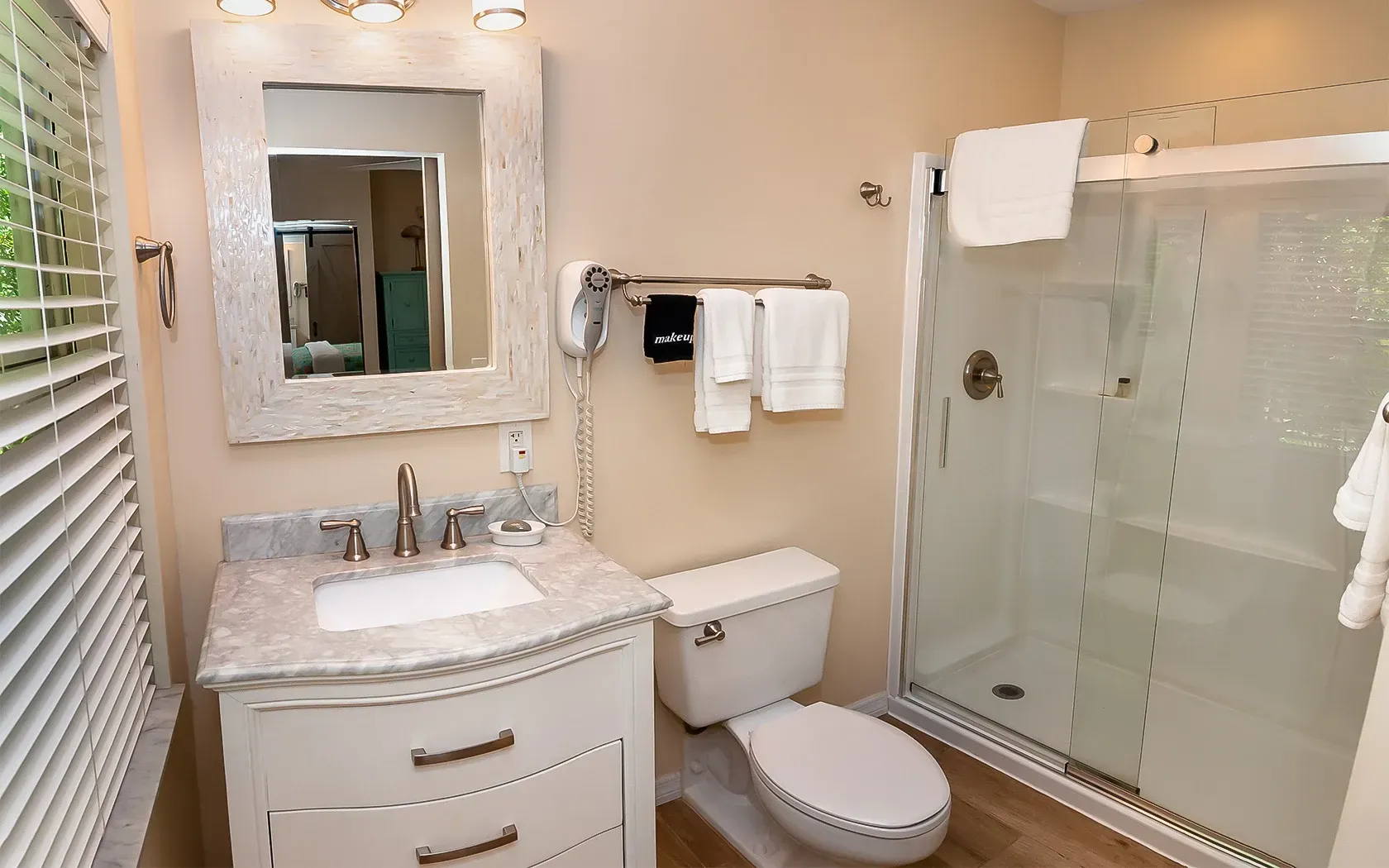 A bathroom with a toilet , sink , mirror and walk in shower.