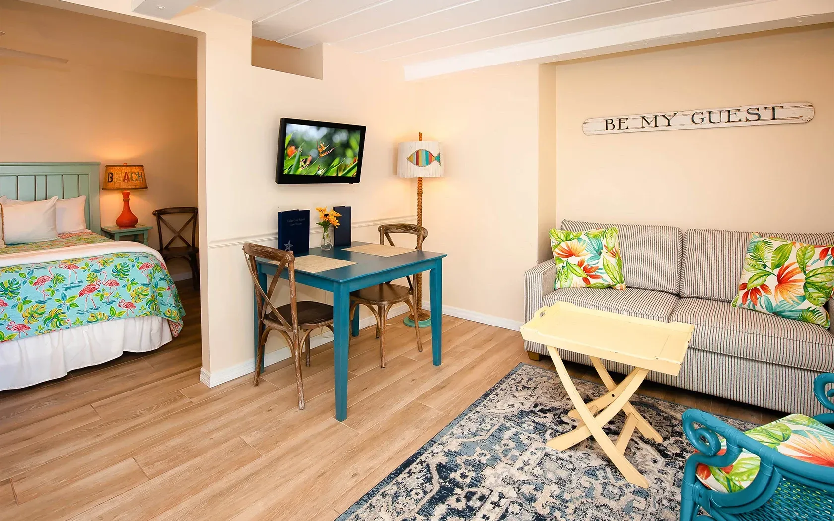 A hotel room with a couch , table , chairs and a television.