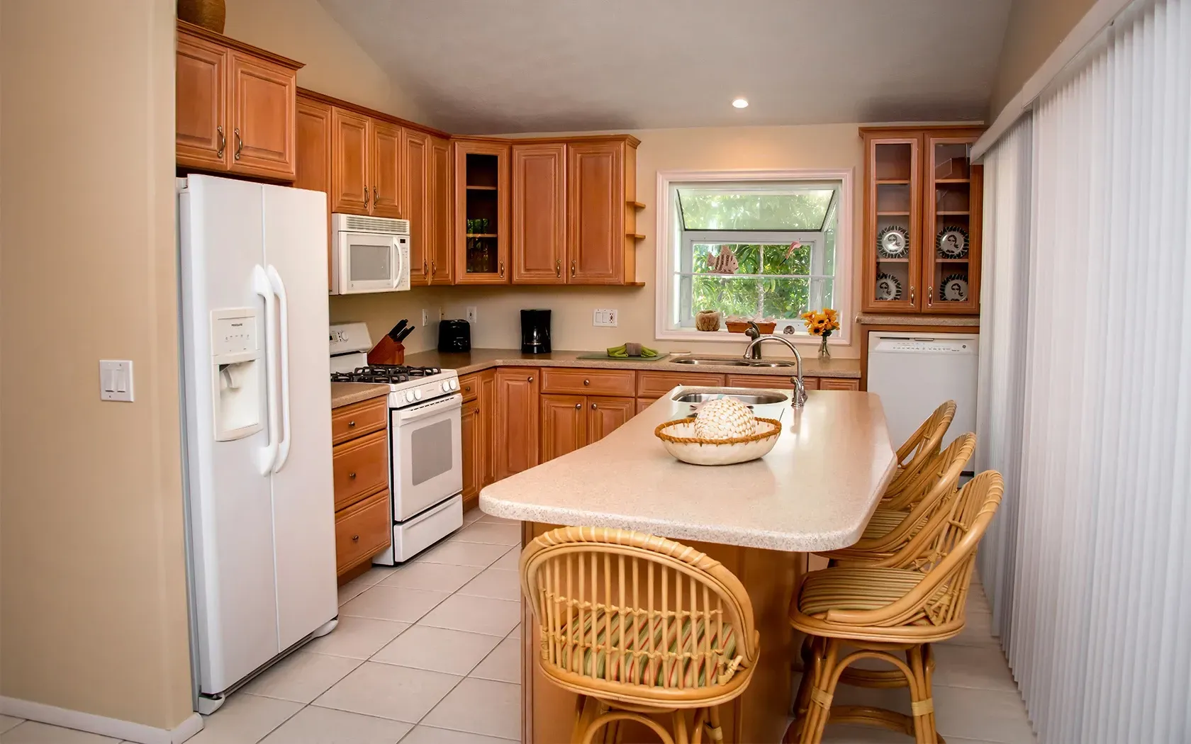 A kitchen with a large island and wicker chairs